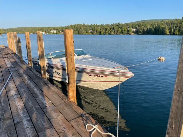 A 1992 Powerquest 270 Laser docked at a wooden pier on a calm lake.