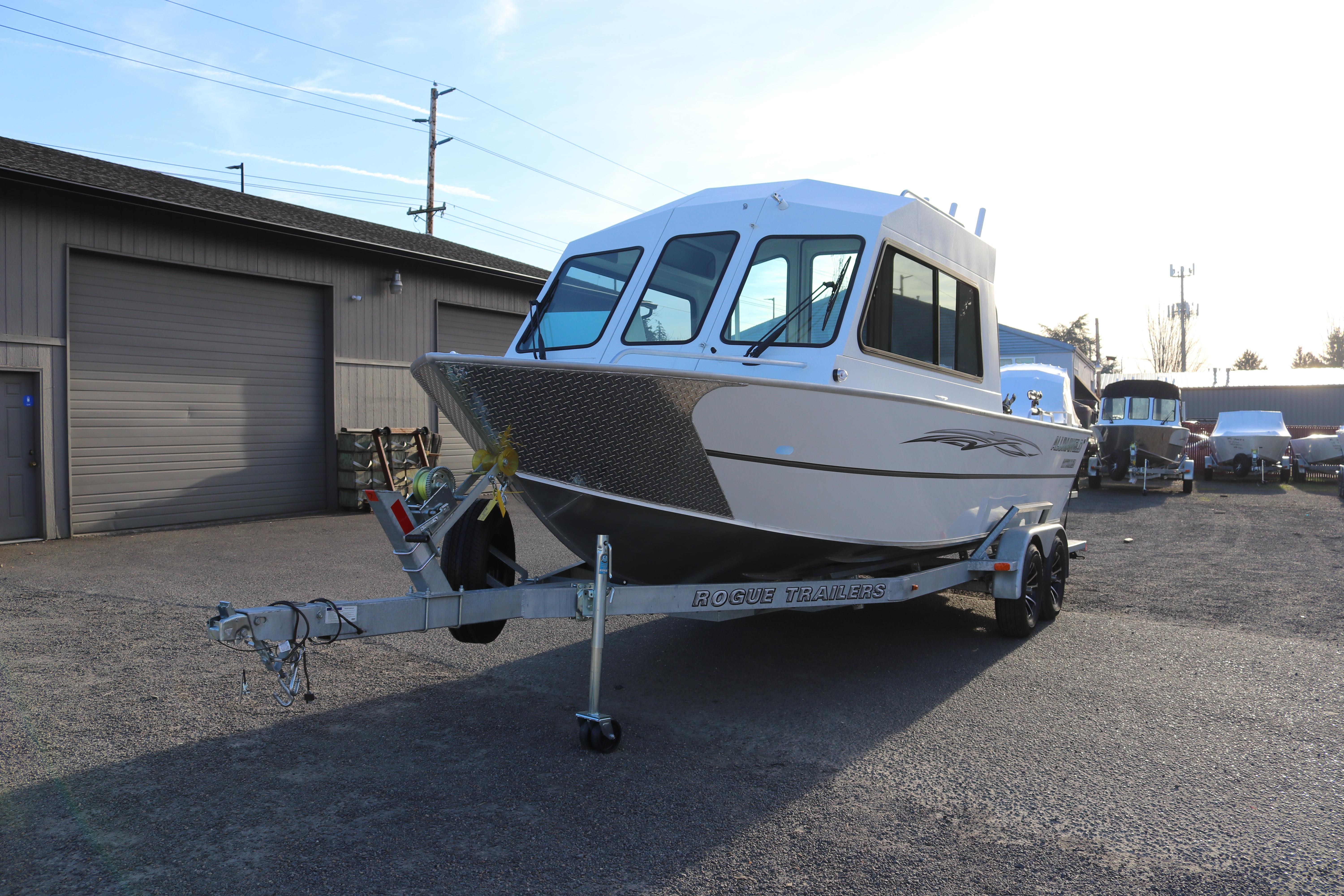 2026 Alumaweld Intruder Outboard 22 boat on Rogue trailer in a parking lot.