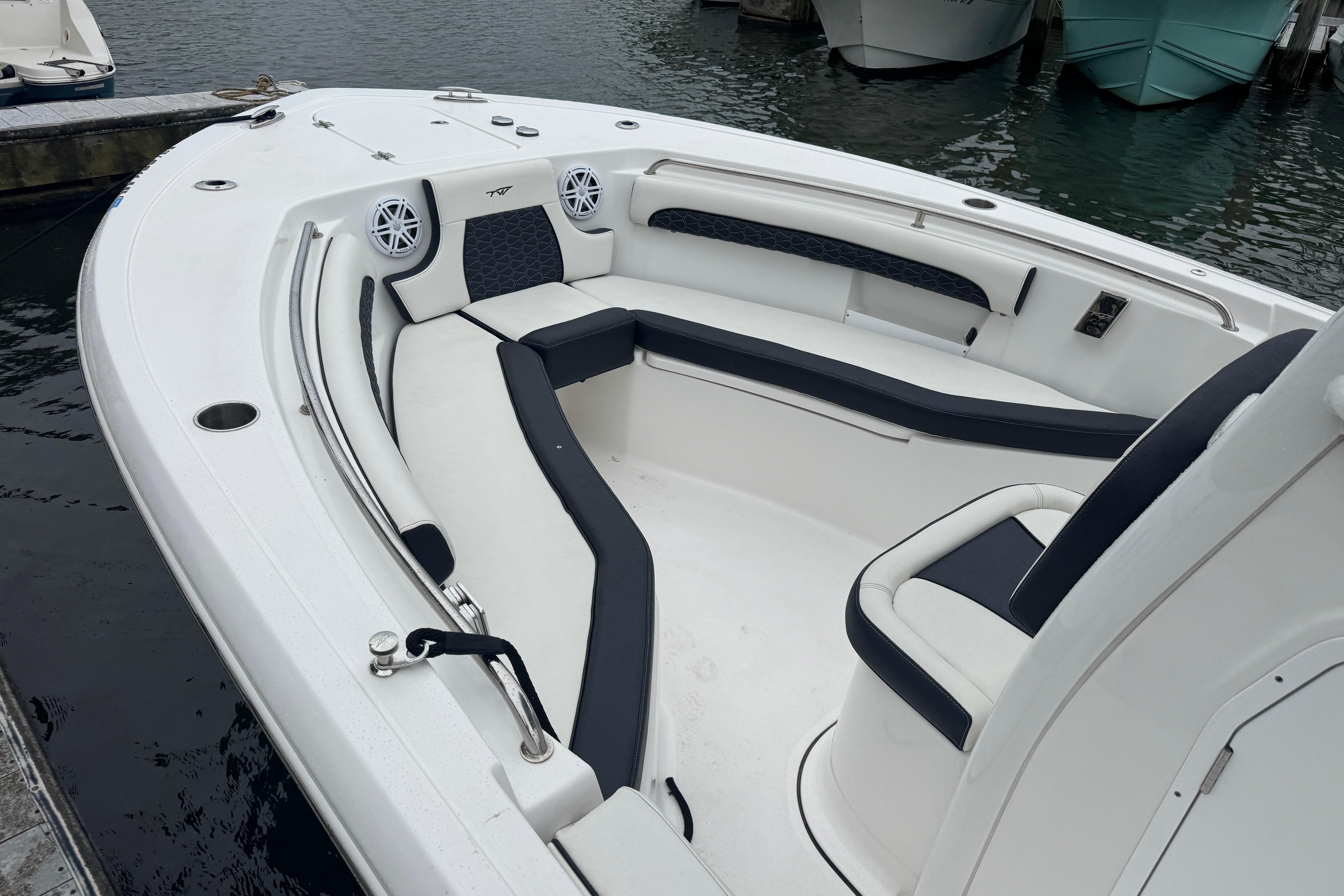 2025 Tidewater 232 LXF boat interior with cushioned seating and speakers, docked by the water.