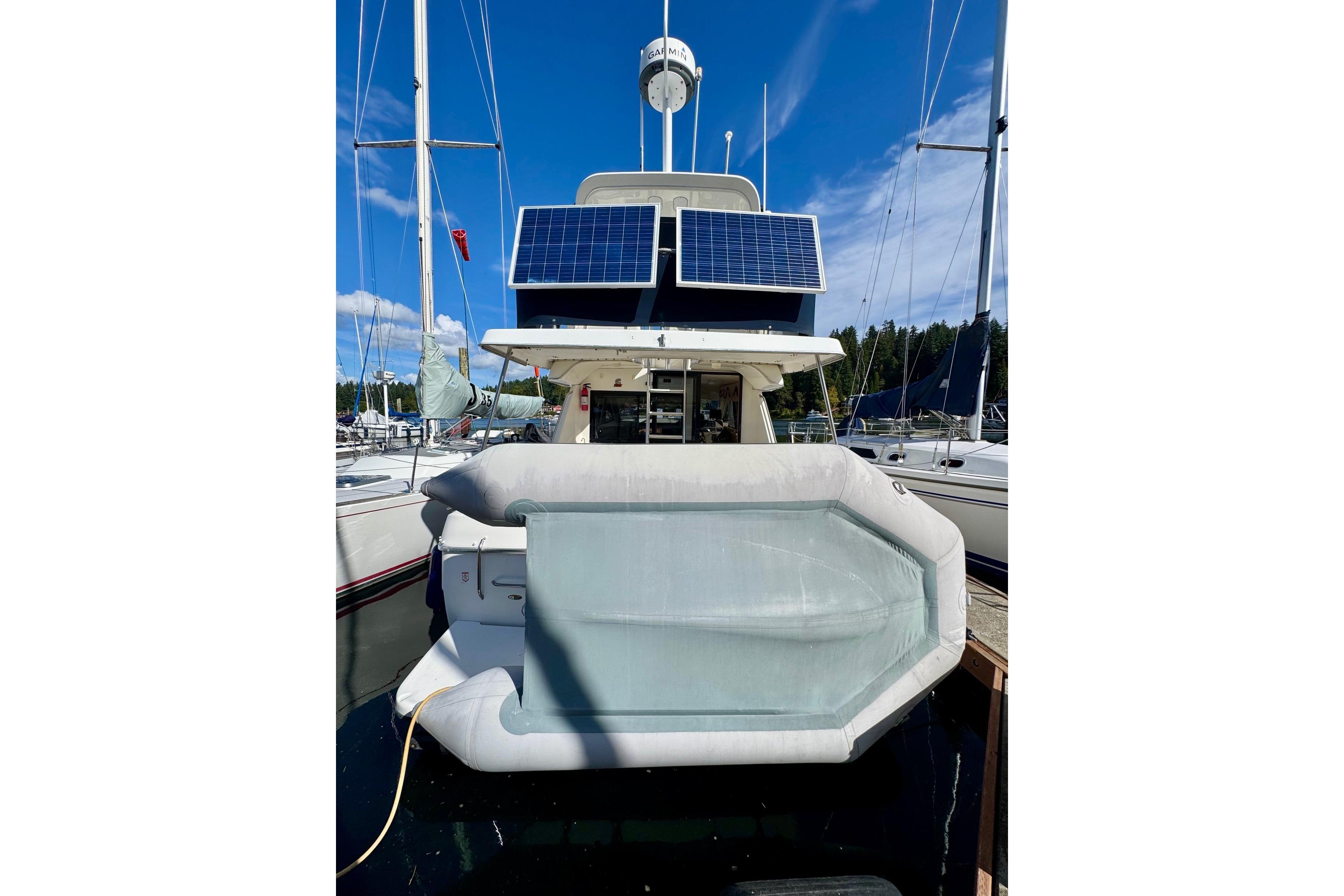 1998 Bayliner 3388 Command Bridge Motoryacht with solar panels and inflatable boat at marina.