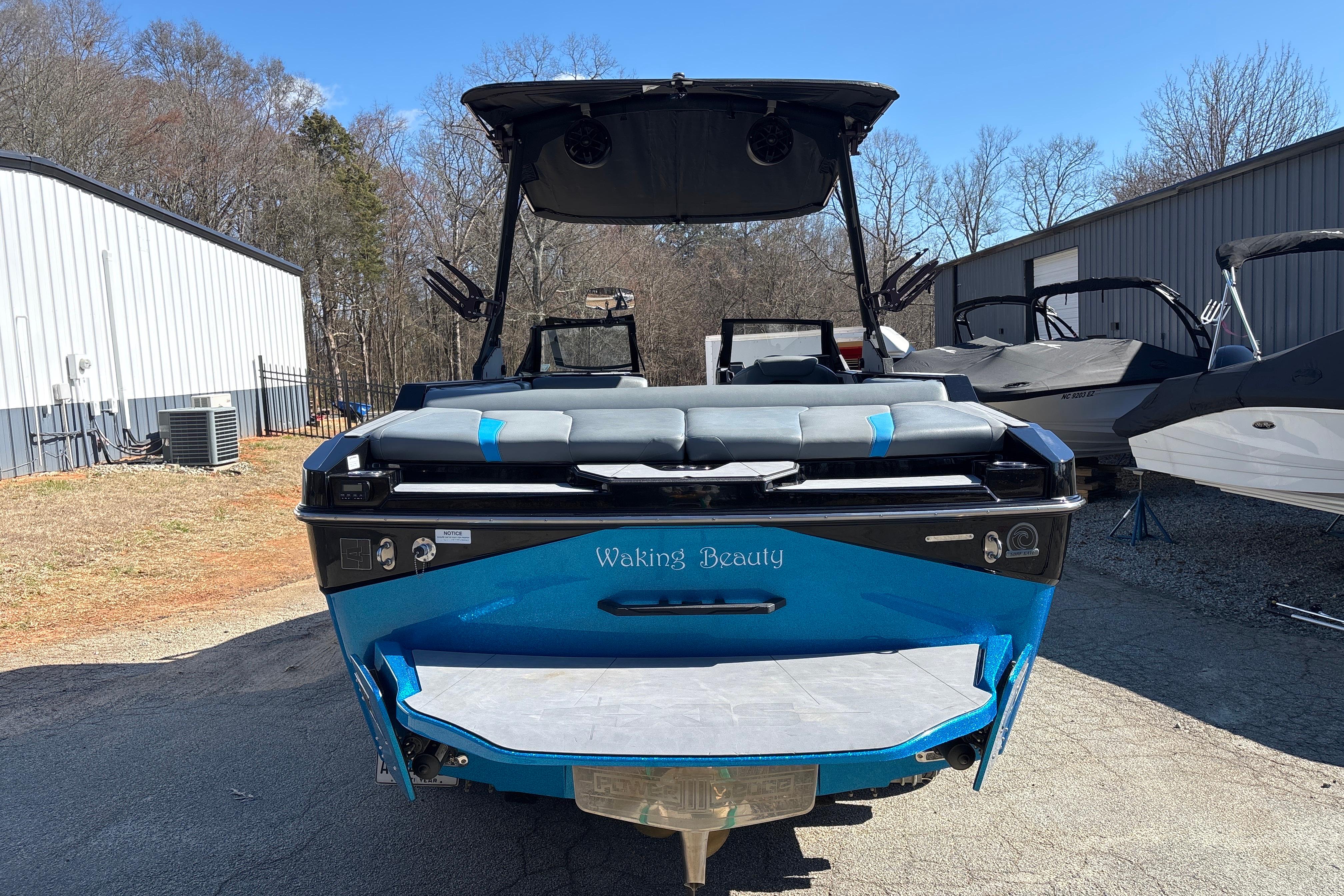 2023 Axis T220 boat, blue, rear view, parked outdoors near buildings.