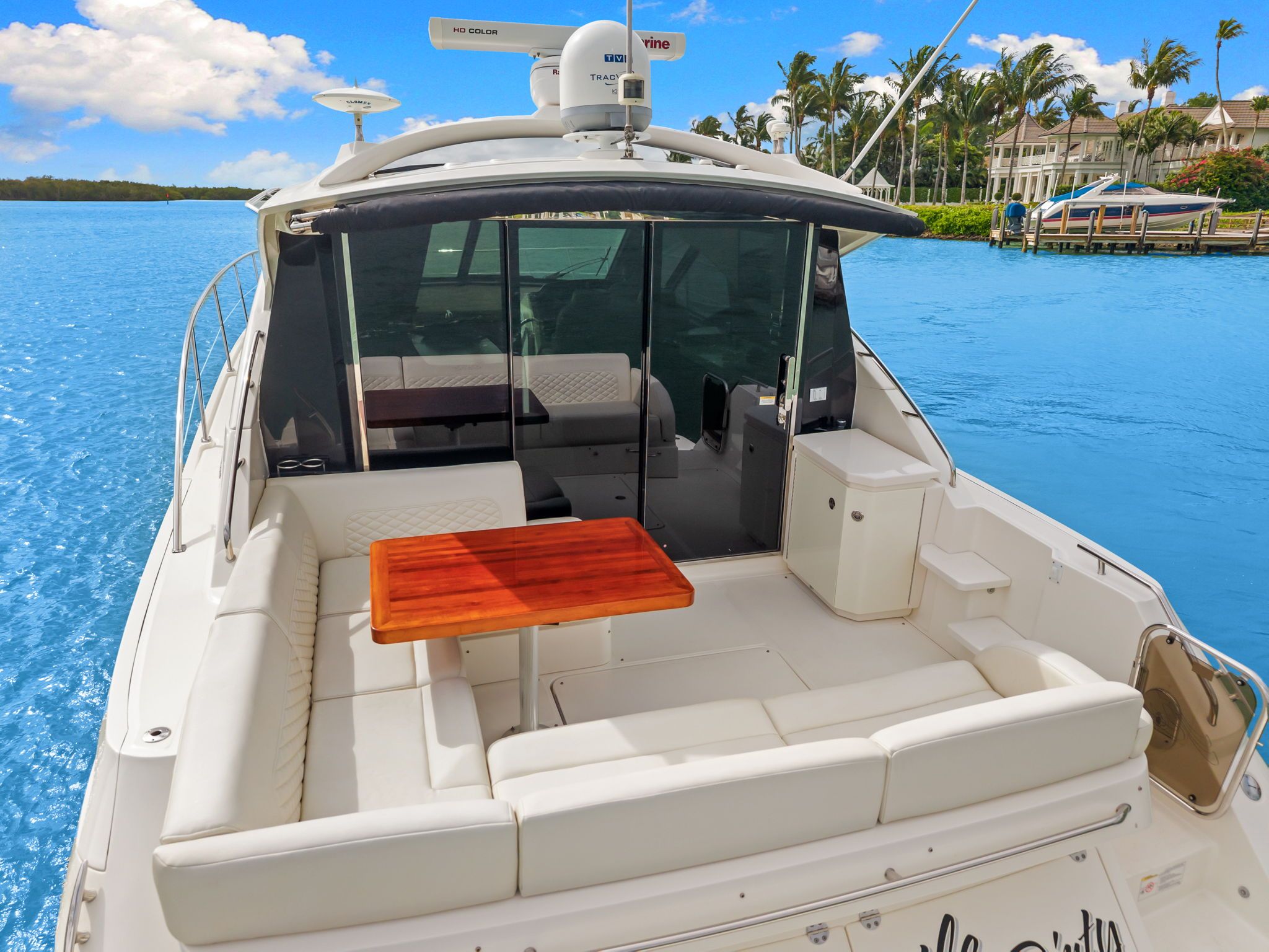 A luxurious yacht with a sleek white deck and wooden table, on calm water.