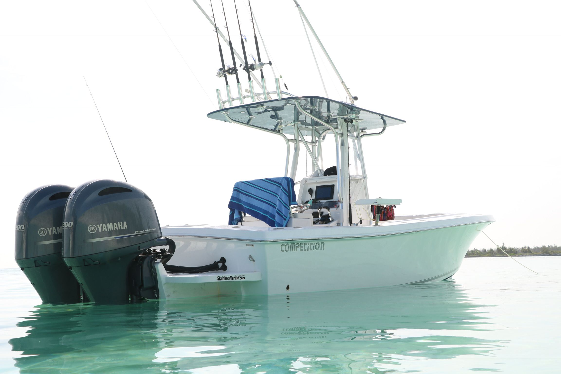 A white boat with two Yamaha engines floats on calm water.