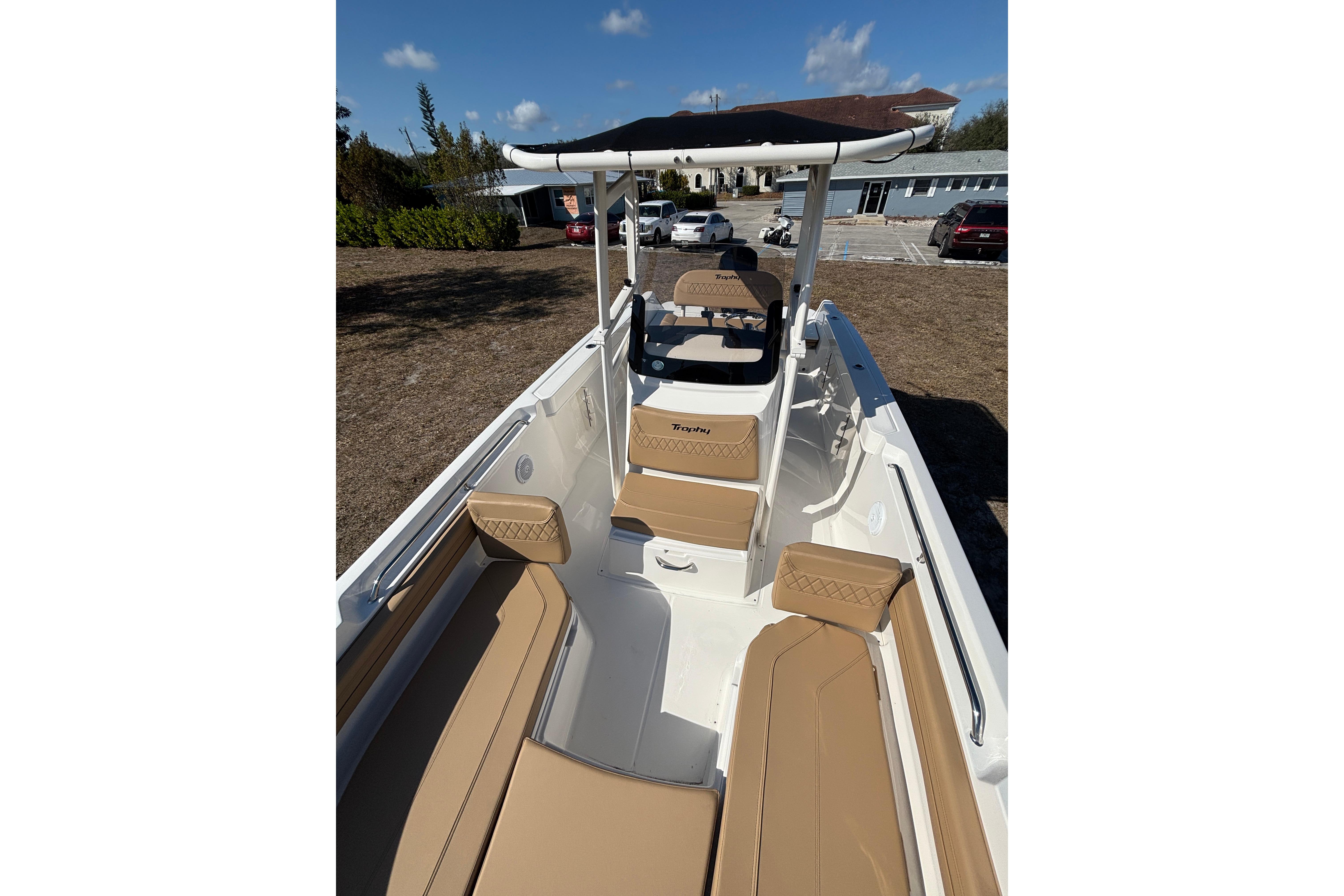 2026 Bayliner Trophy T22CC boat with tan seating and canopy, parked outdoors.