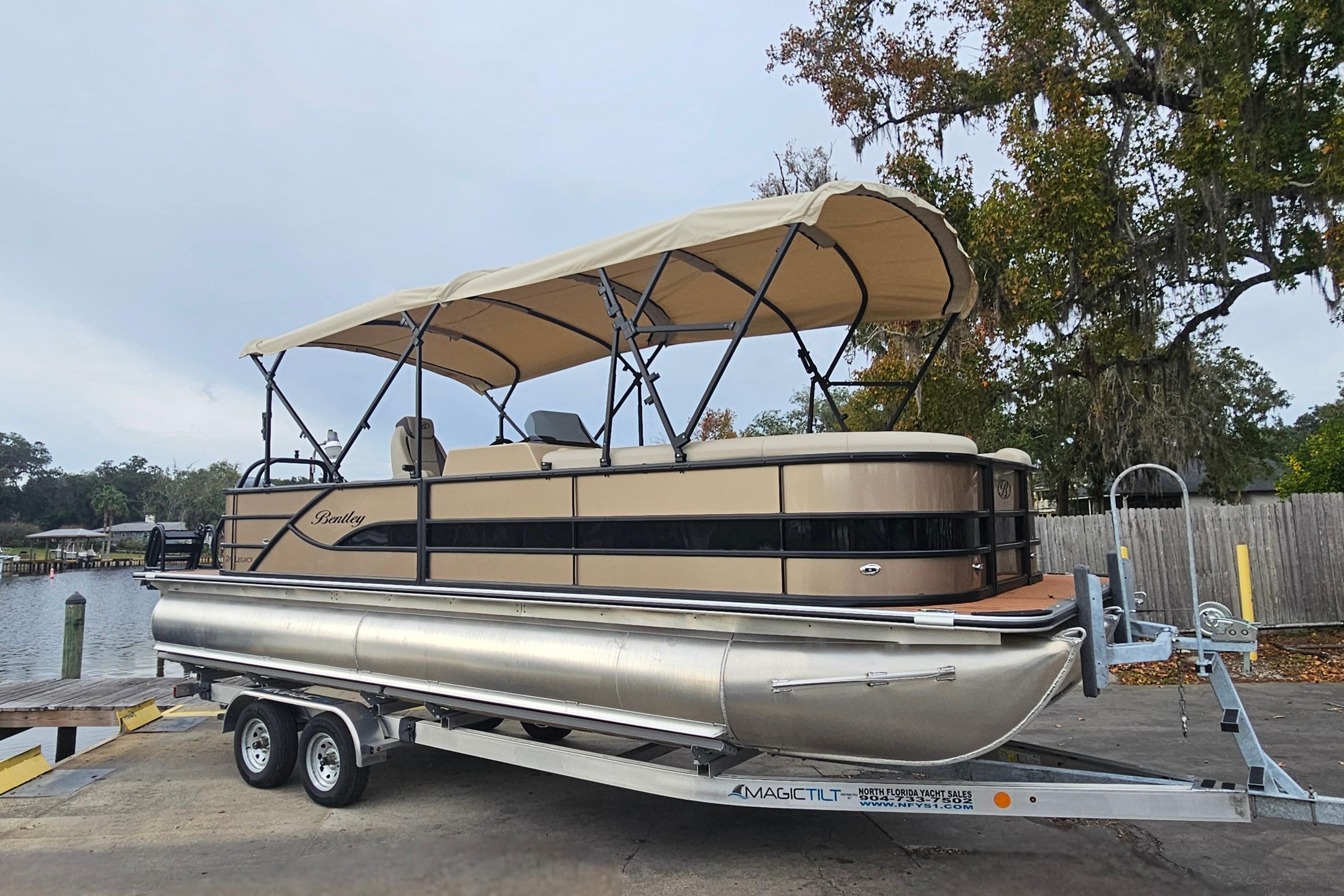 2026 Bentley Pontoons Legacy 243 Cruise on trailer, beige canopy, parked near water.
