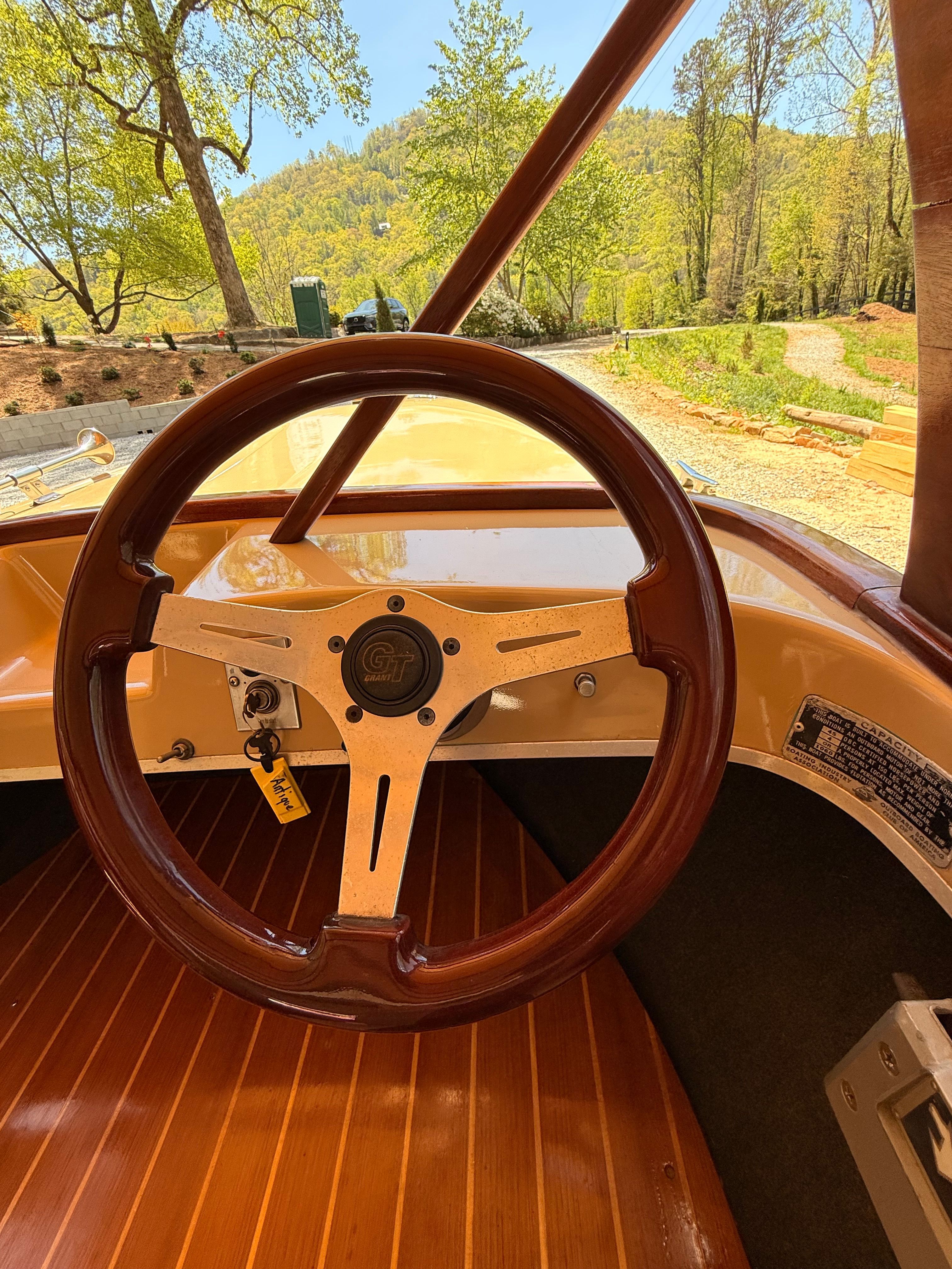 A vintage boat with a wooden steering wheel and sleek dashboard.