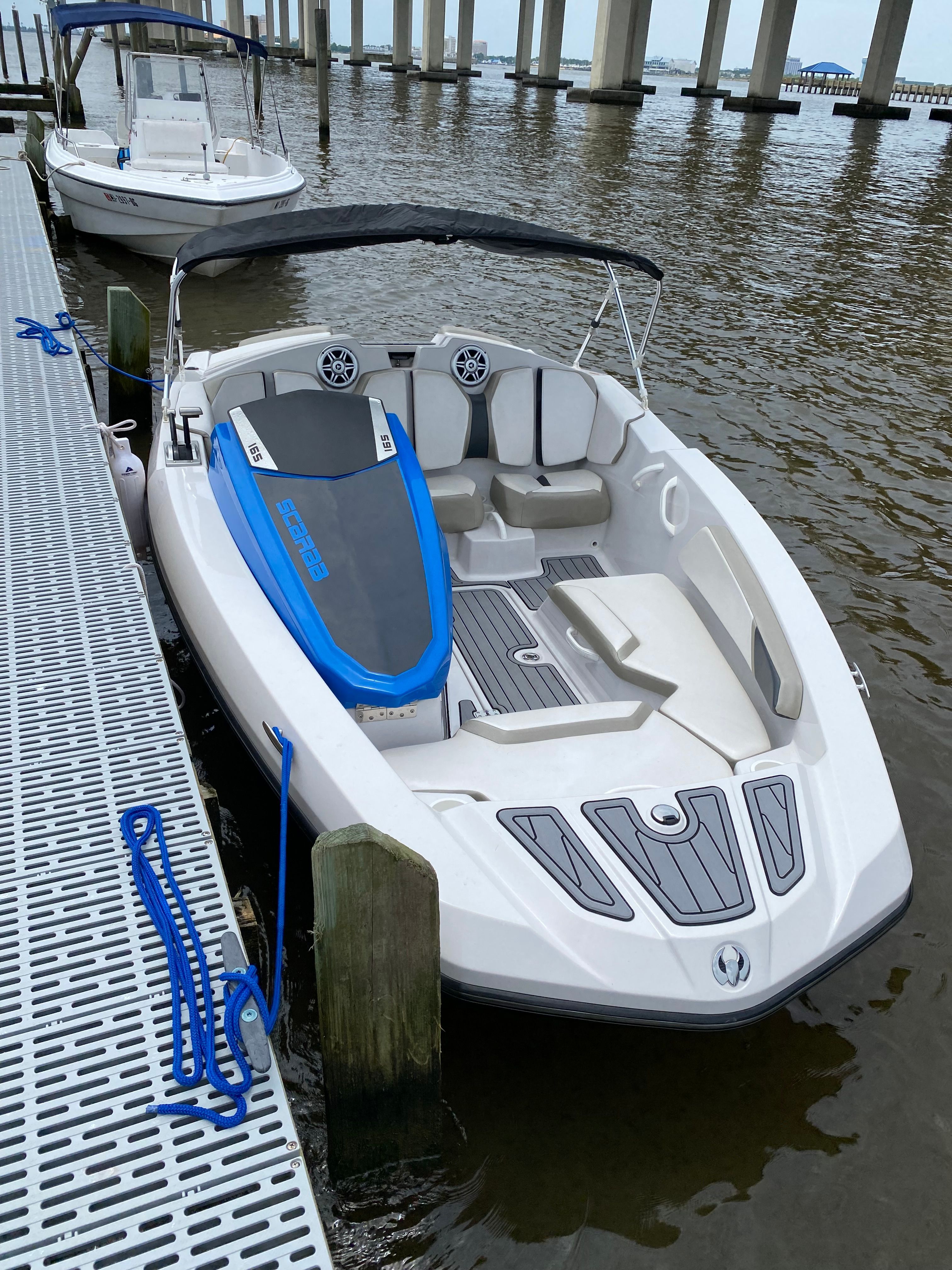 A 2015 Scarab 165 boat docked on the water. It features a blue and white design.