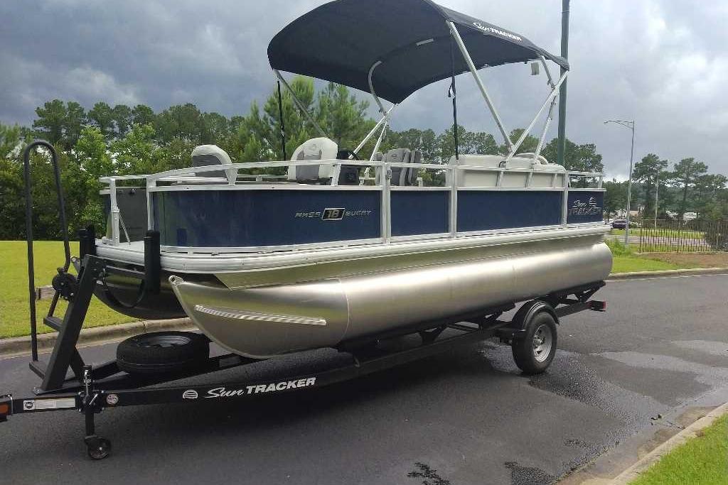 2026 Sun Tracker Bass Buggy 18 DLX pontoon boat on trailer, parked outdoors.