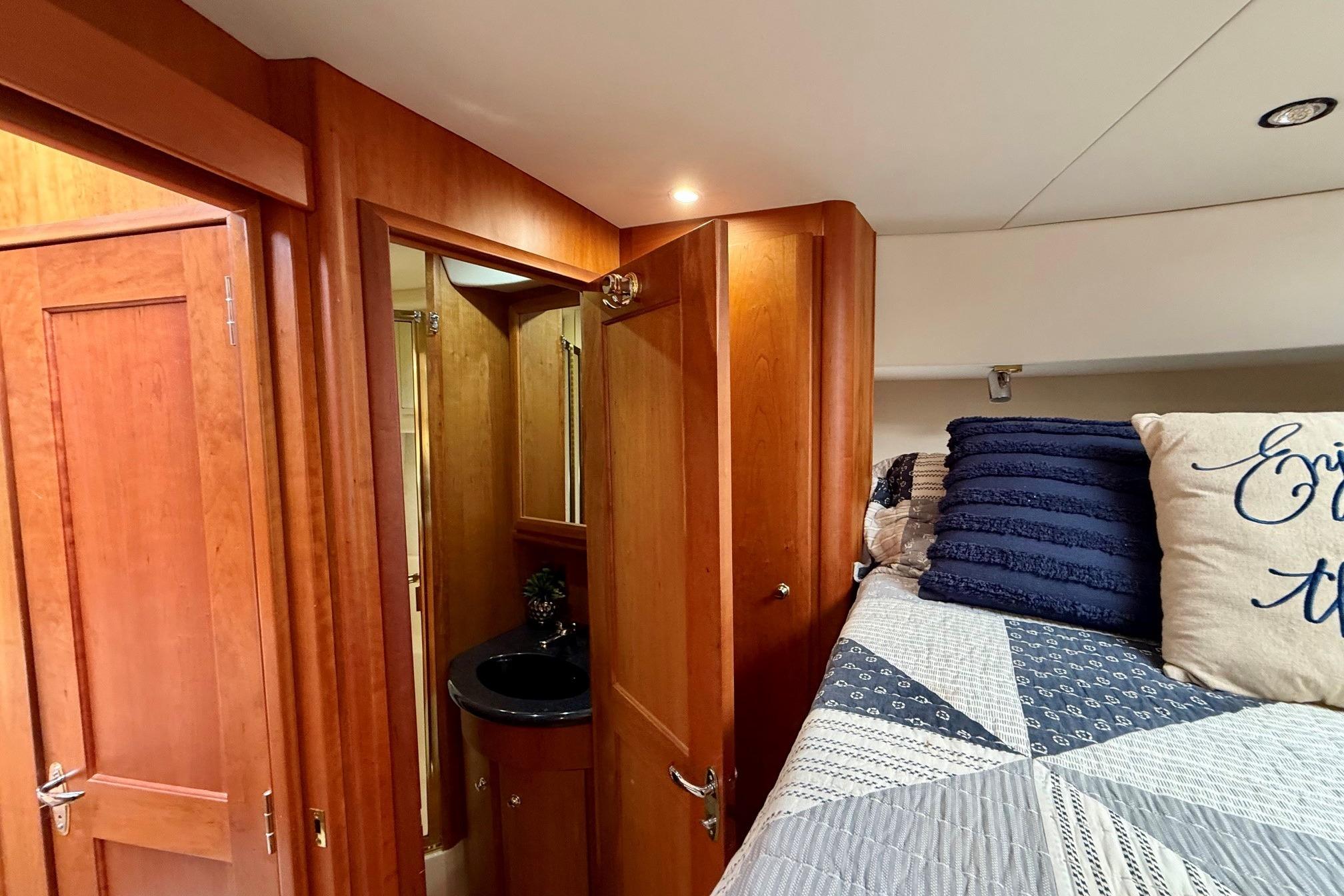 Interior of 2004 Silverton 39 Motor Yacht with cozy bedroom and wooden cabinetry.