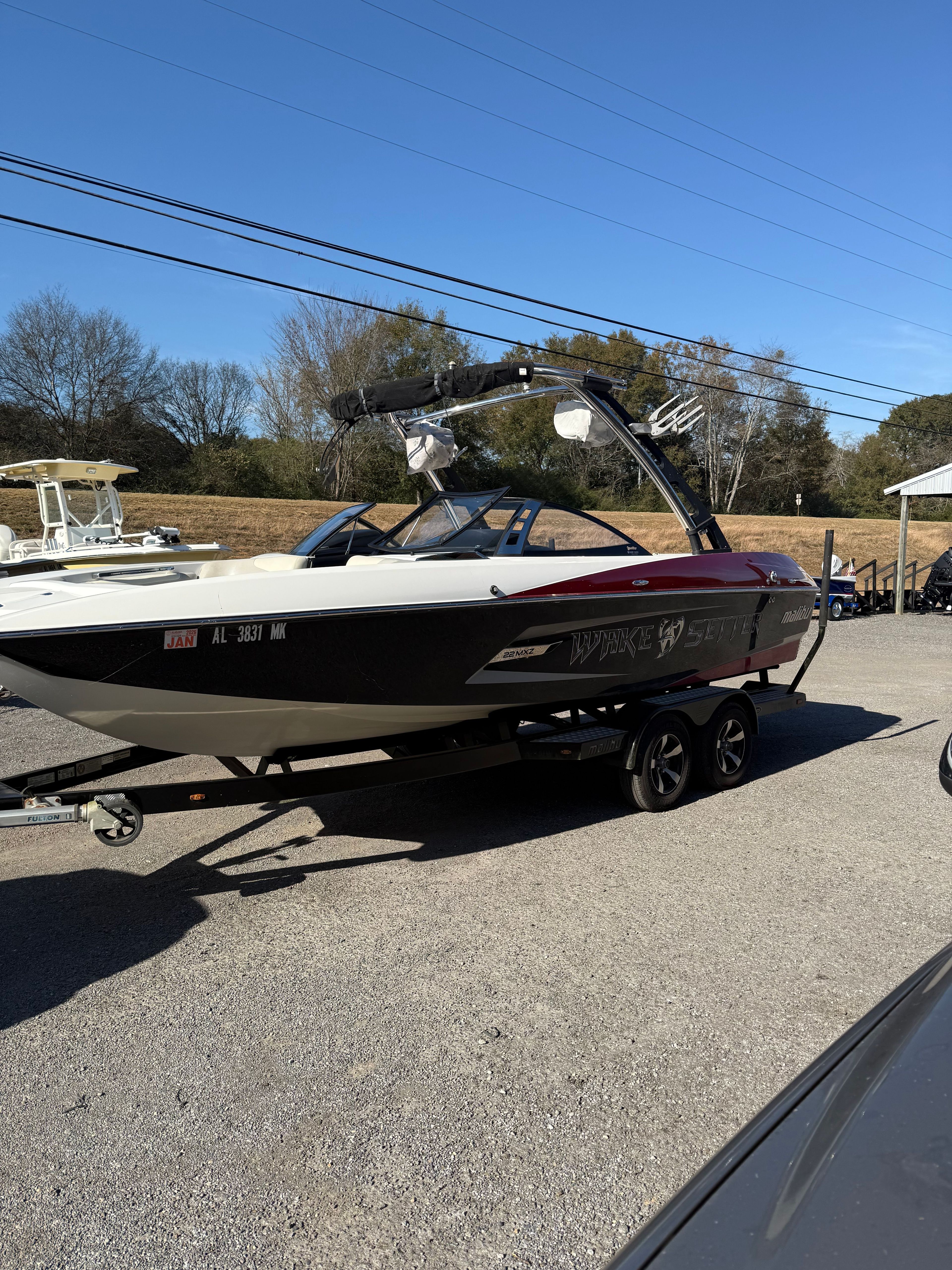 A 2013 Malibu Wakesetter 22 MXZ on a trailer in a parking lot.