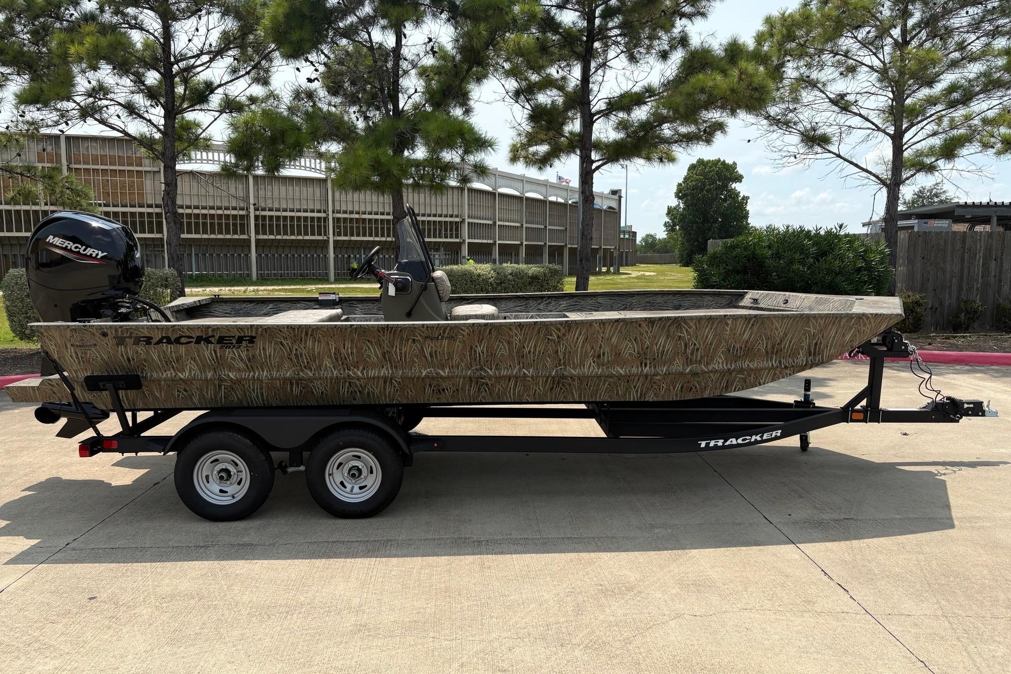 2026 Tracker Grizzly 2072 CC boat on trailer, parked outdoors with trees in background.