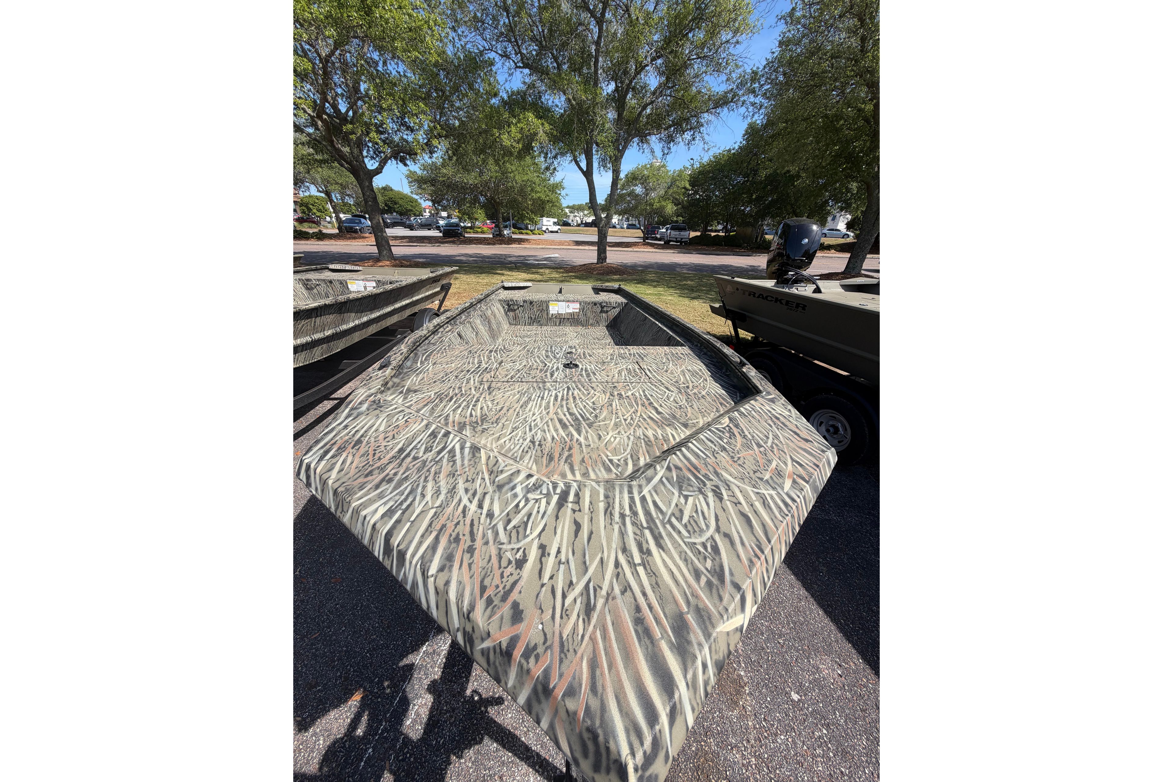 2026 Tracker Grizzly 1648 Utility boat with camouflage design in a park setting.