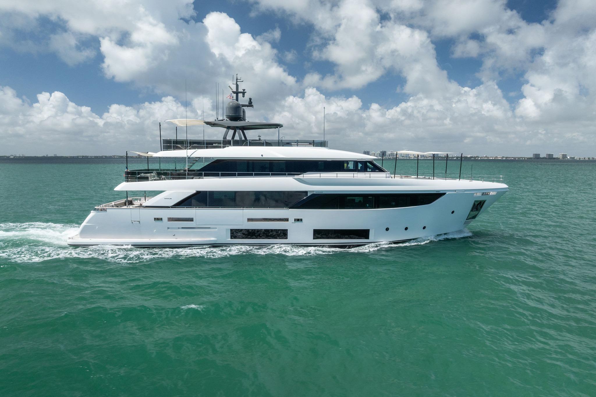 Luxurious 2023 Custom Line Navetta 33 yacht cruising on turquoise waters under a cloudy sky.