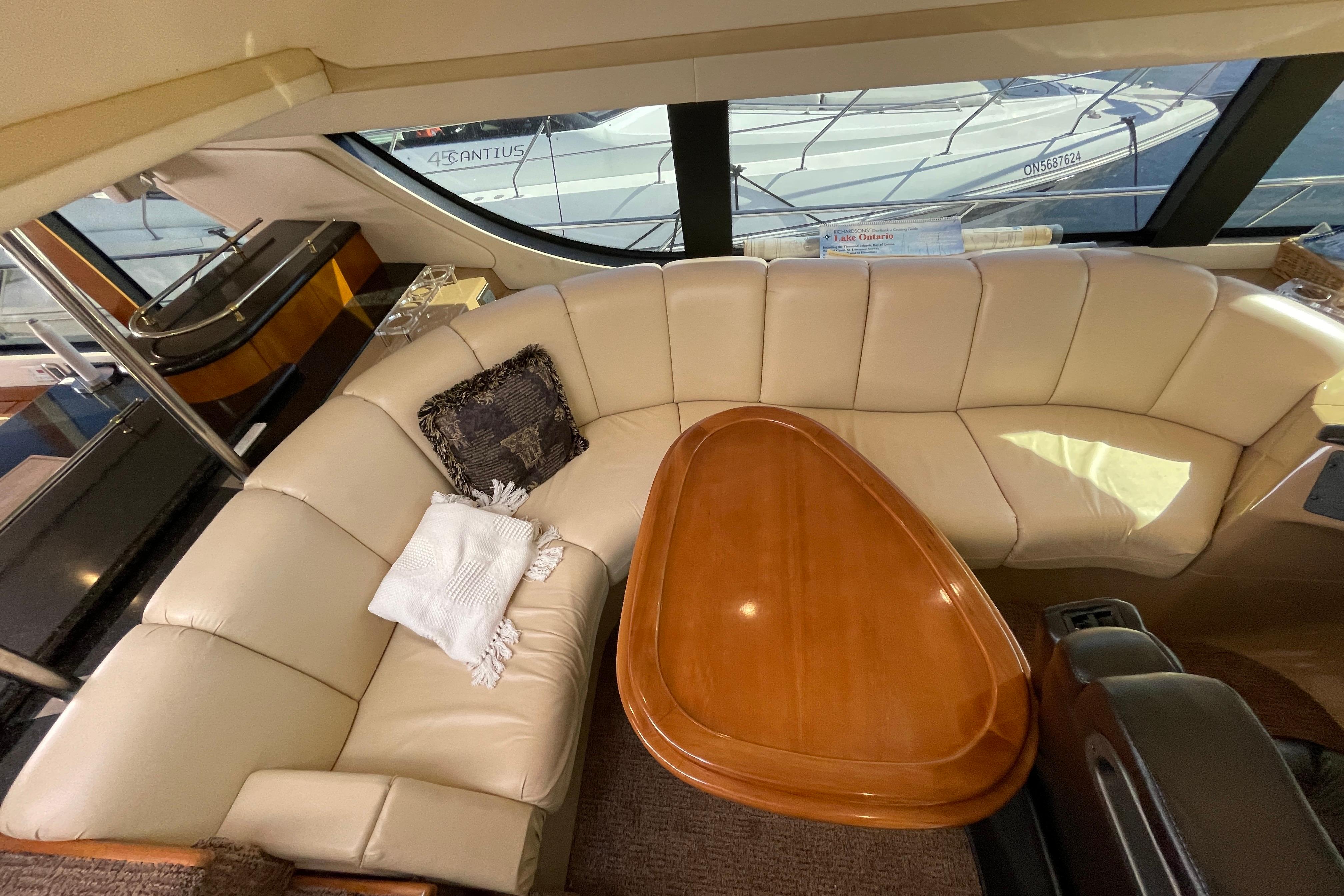 Luxurious interior of 2002 Carver 570 Voyager Pilothouse with cream leather seating and wooden table.