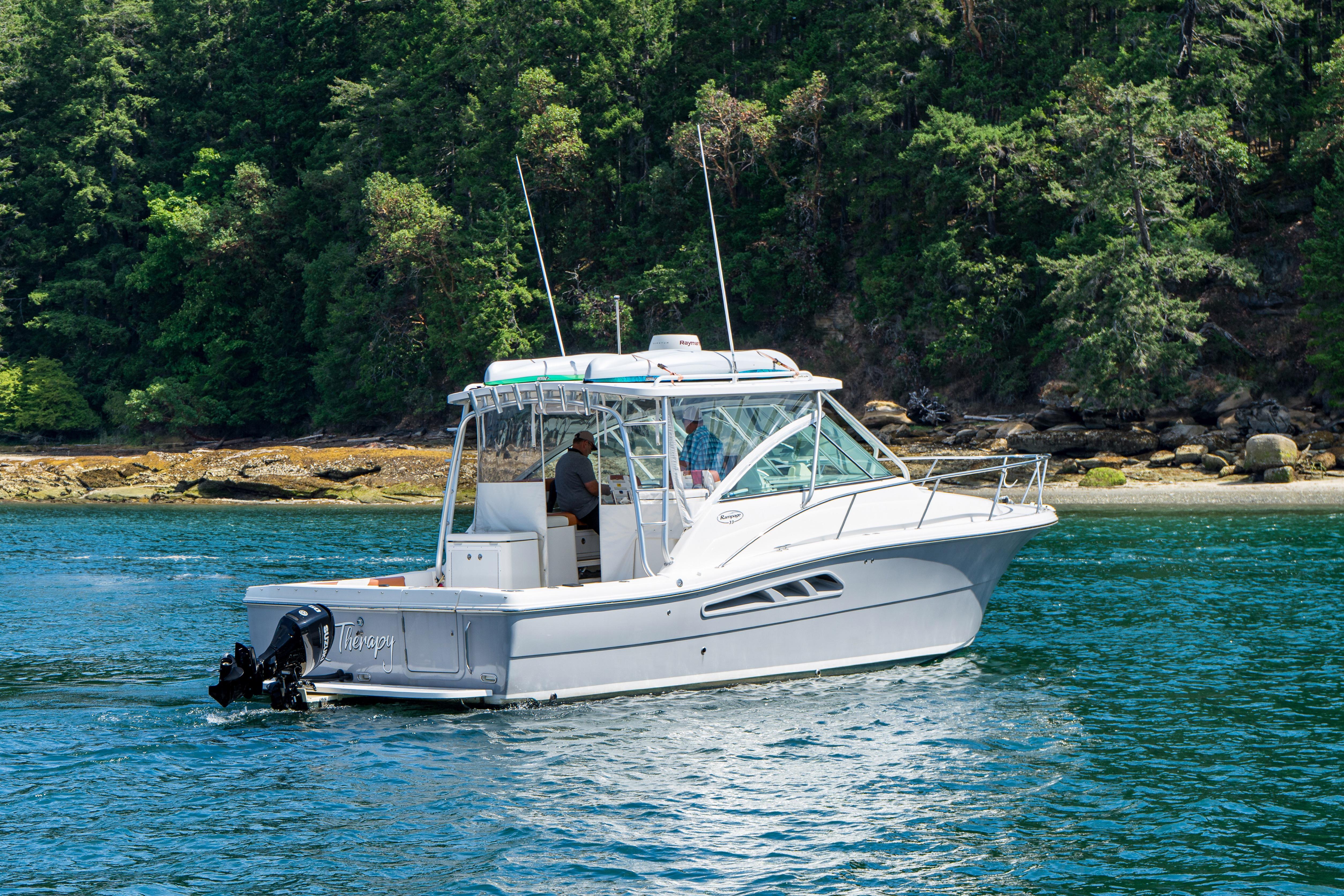 2005 Rampage 33 Express boat cruising near a forested shoreline.