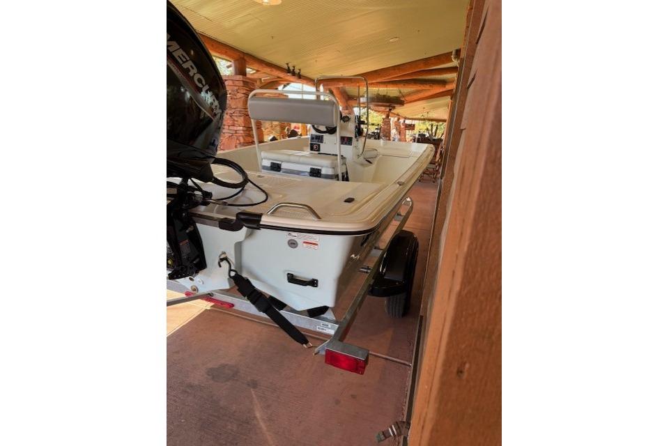 2026 Mako Pro Skiff 17 CC boat on trailer, parked under a wooden canopy.