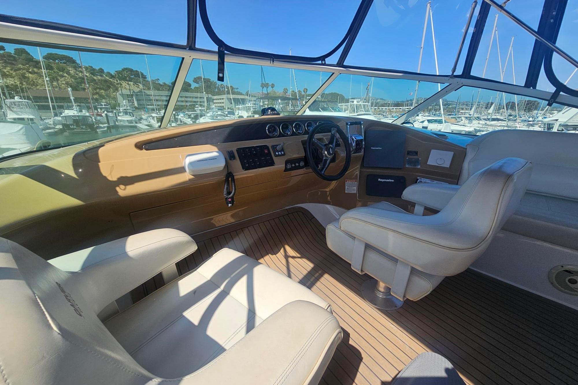 Pilothouse interior of 2002 Carver 450 Voyager, featuring helm and seating, docked at marina.