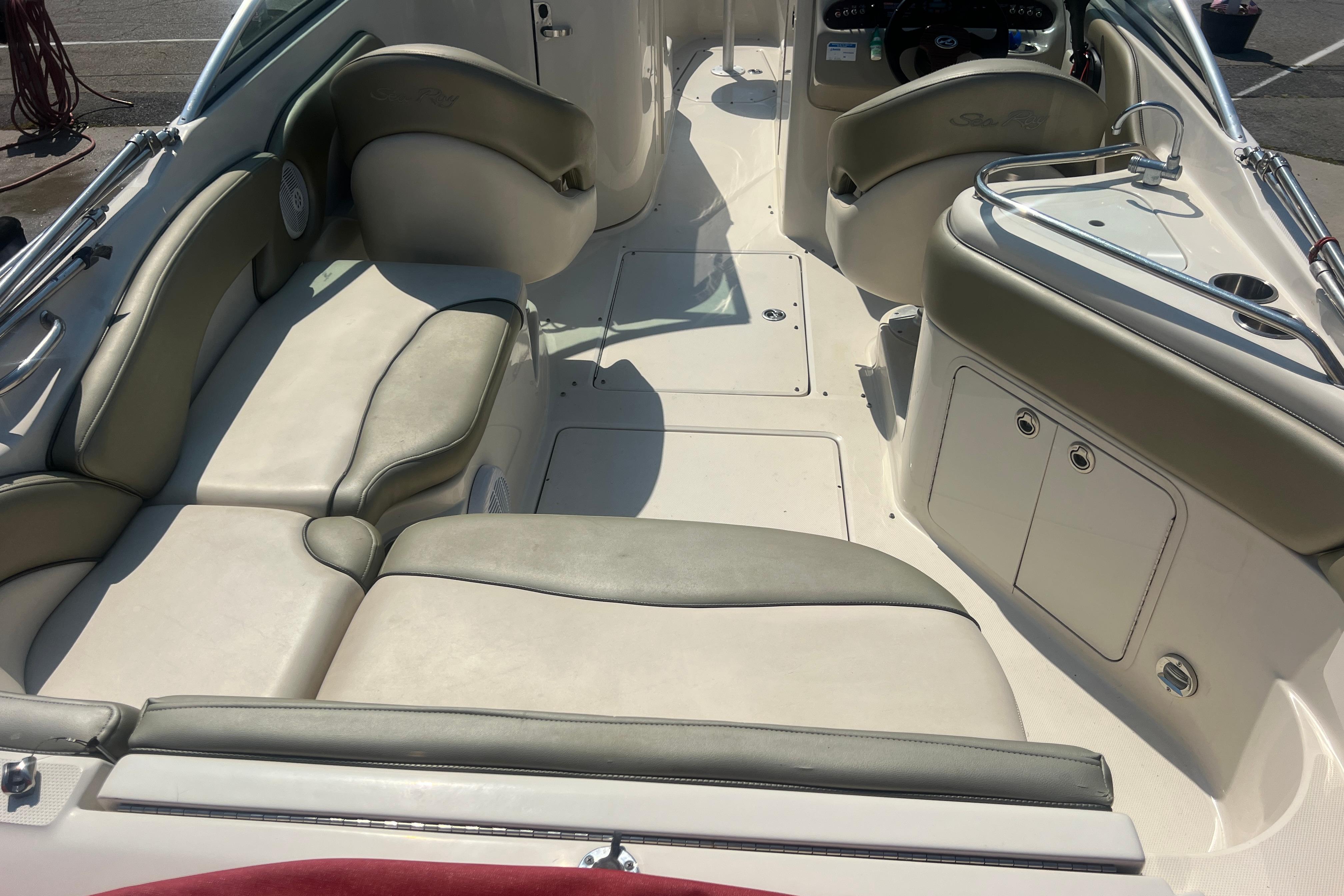 Interior view of a 2005 Sea Ray 240 Sundeck boat with beige seating and helm.