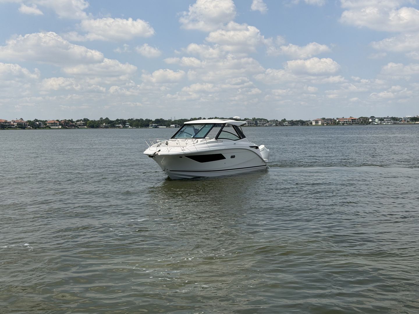 2026 Sea Ray Sundancer 320 Outboard on calm water under cloudy sky.