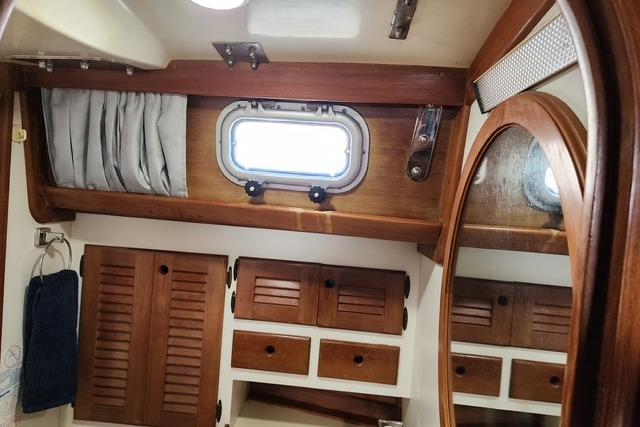 1984 Bristol 45.5 Center Cockpit interior with wooden cabinets and porthole window.