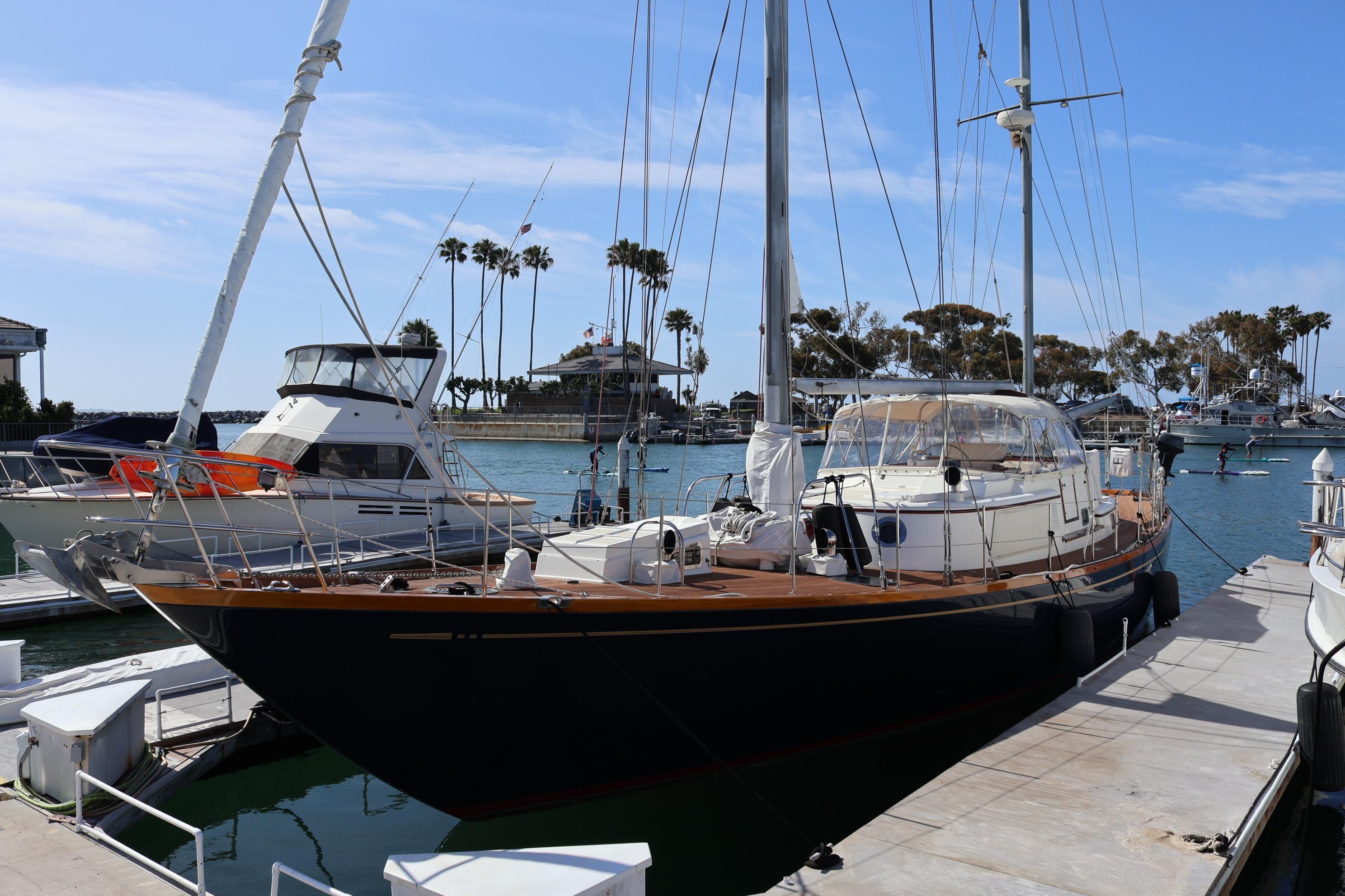 Sailboat docked at marina, Mason 63 model, 1984, with clear blue sky and palm trees.