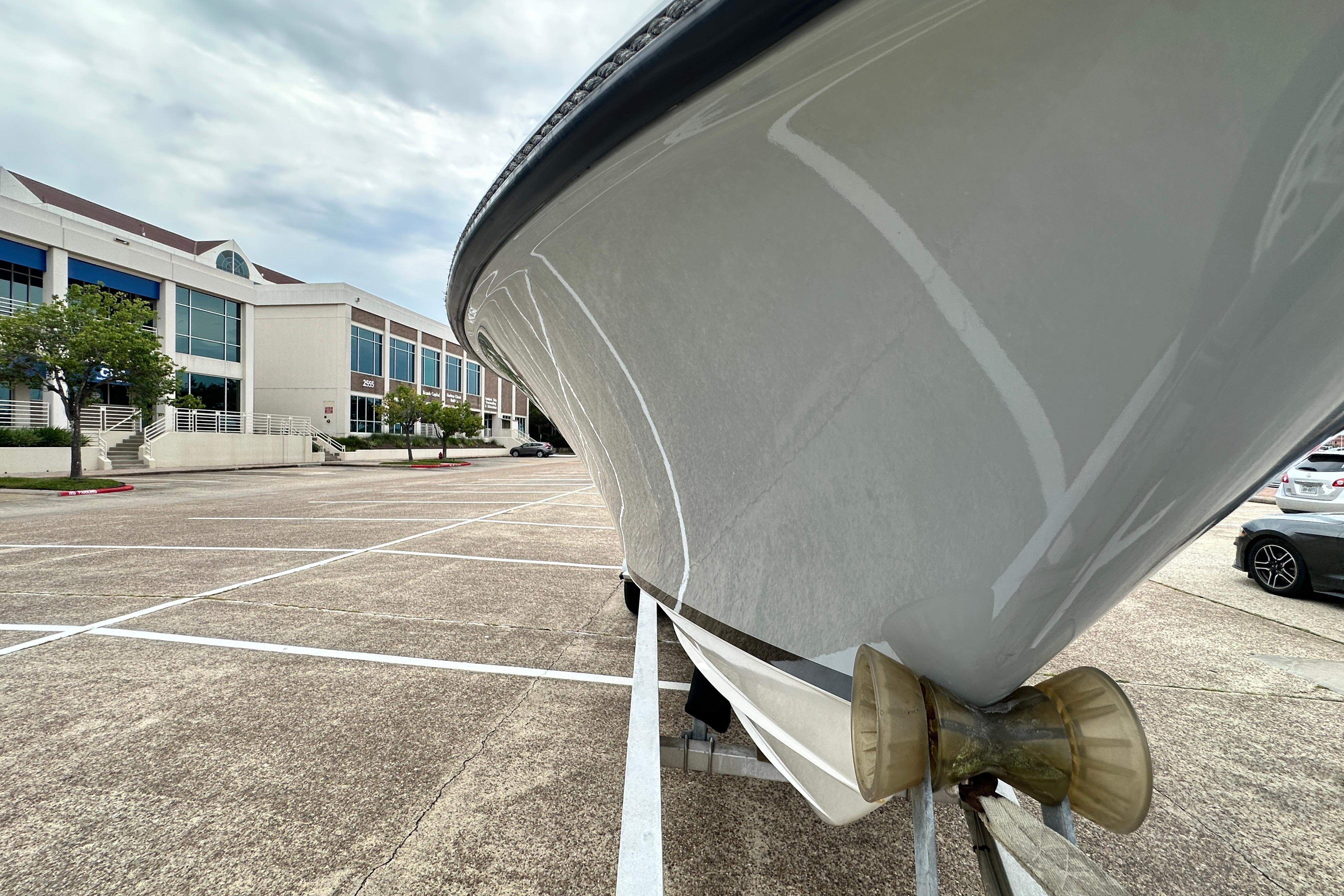 1999 Contender 23 Open boat on trailer in parking lot near modern building.
