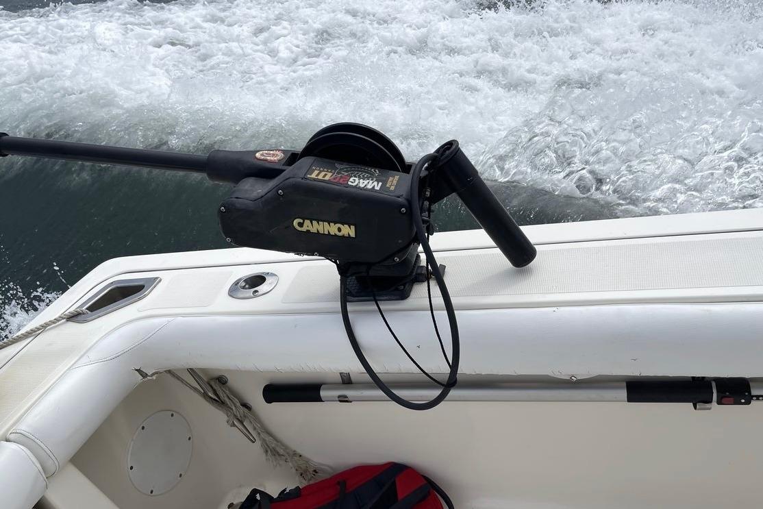 1999 Pursuit 3000 Express boat with Cannon downrigger, ocean waves in background.