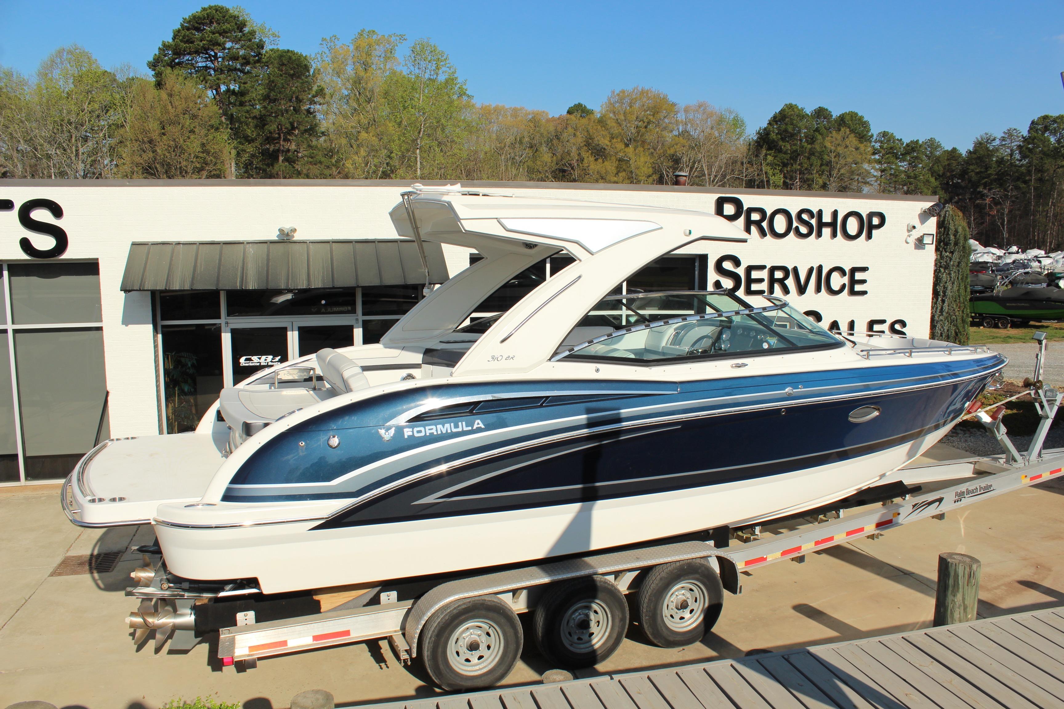 2023 Formula 310 Bowrider I/O boat on trailer at dealership, sunny day.