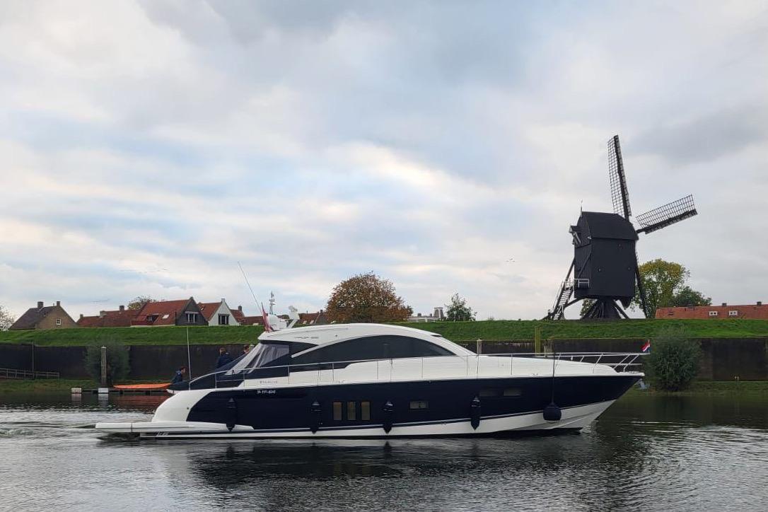 2015 Fairline Targa 62 GT yacht cruising near a traditional windmill.