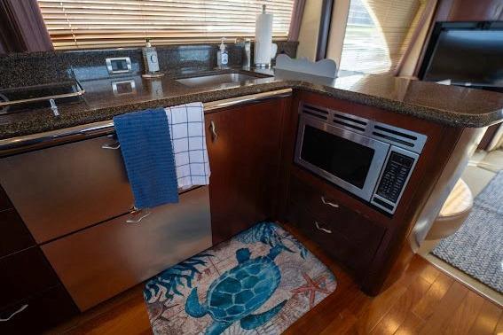 2006 Sea Ray 580 Sedan Bridge kitchen with microwave, sink, and turtle-themed rug.