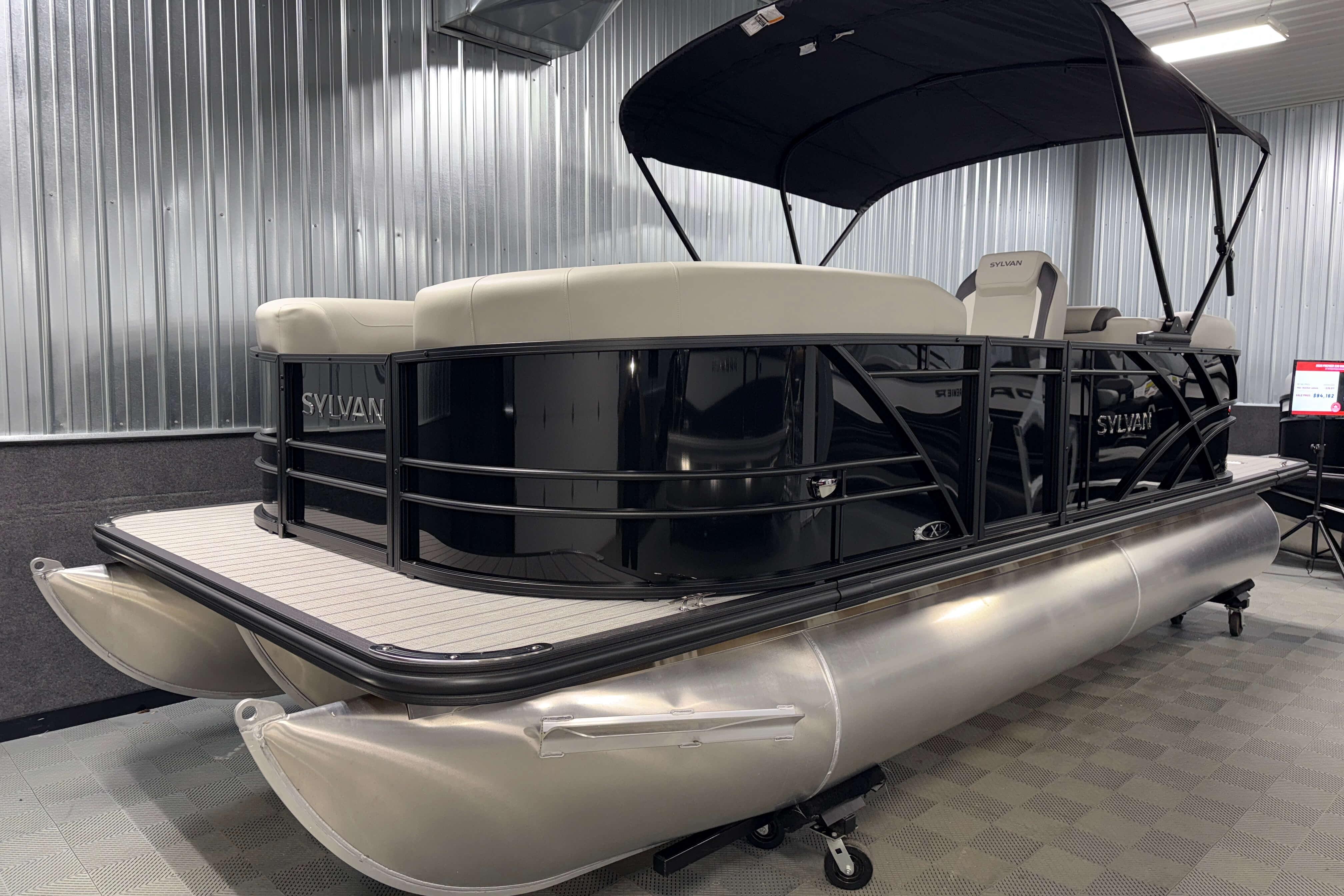 2026 Sylvan Mirage X1 pontoon boat in a showroom, featuring sleek design and modern amenities.