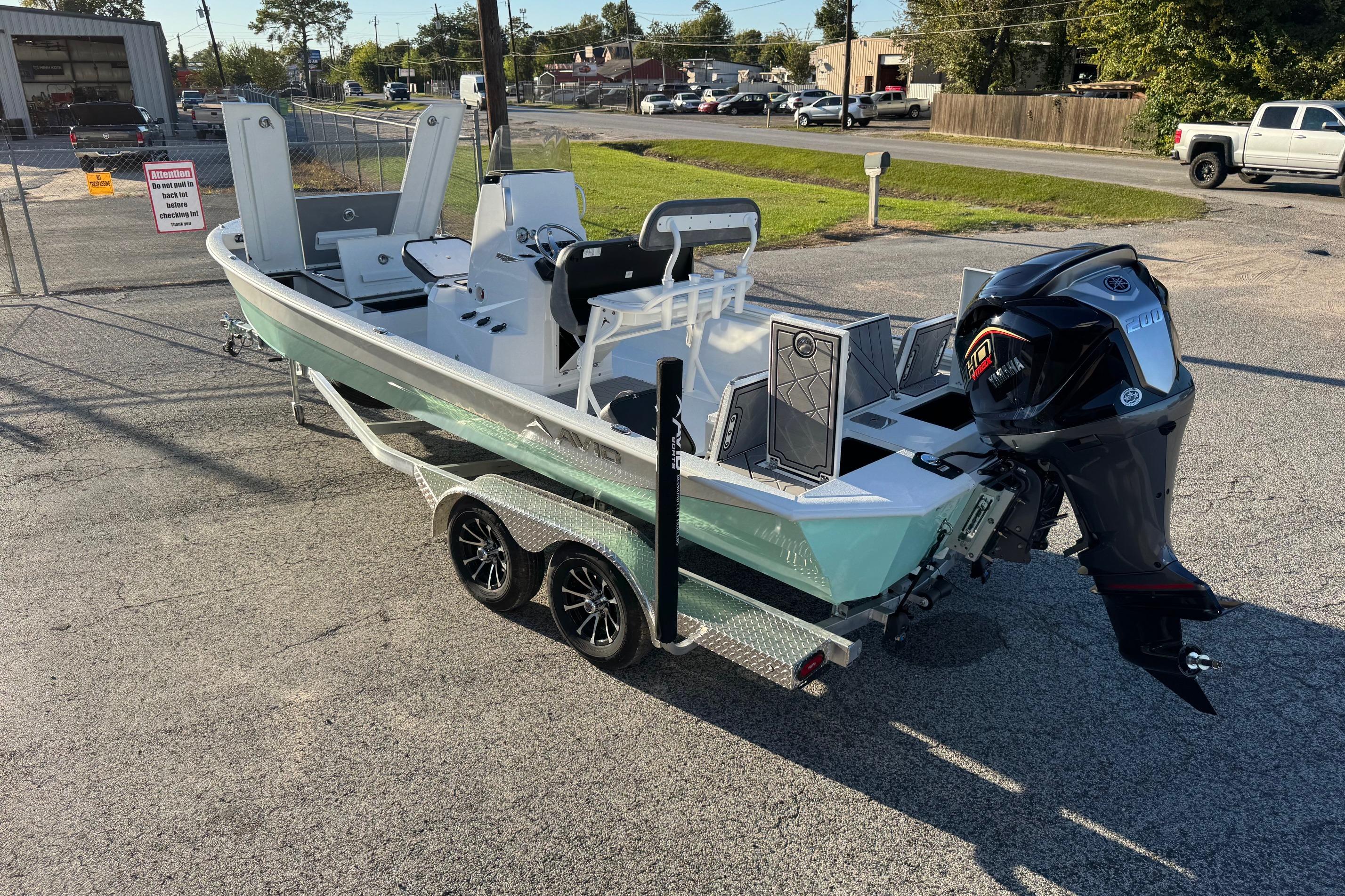 Avid 23 Mag 2025 boat on trailer with powerful outboard motor in parking lot.