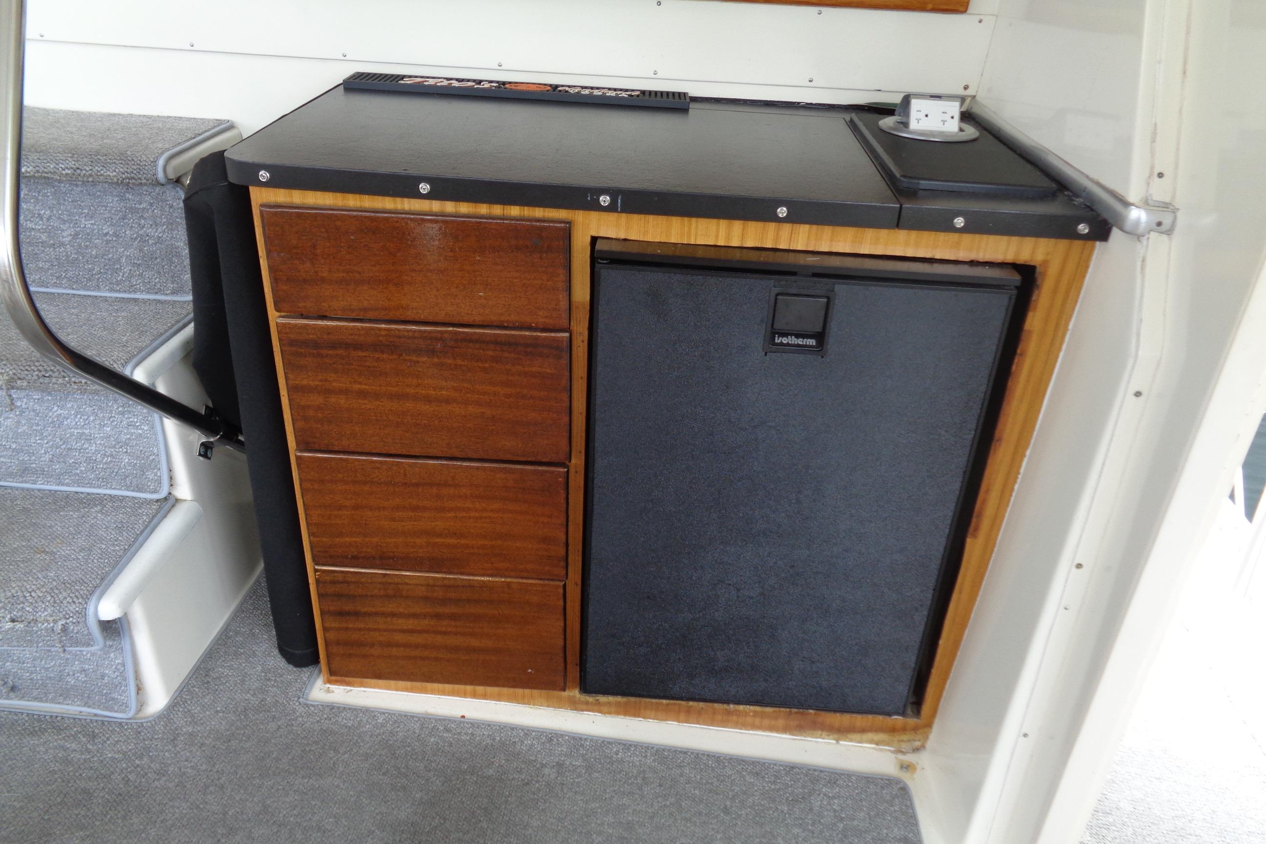 Interior of 1981 Hatteras 48 Cockpit Motor Yacht with wooden cabinetry and mini fridge. Sun Deck