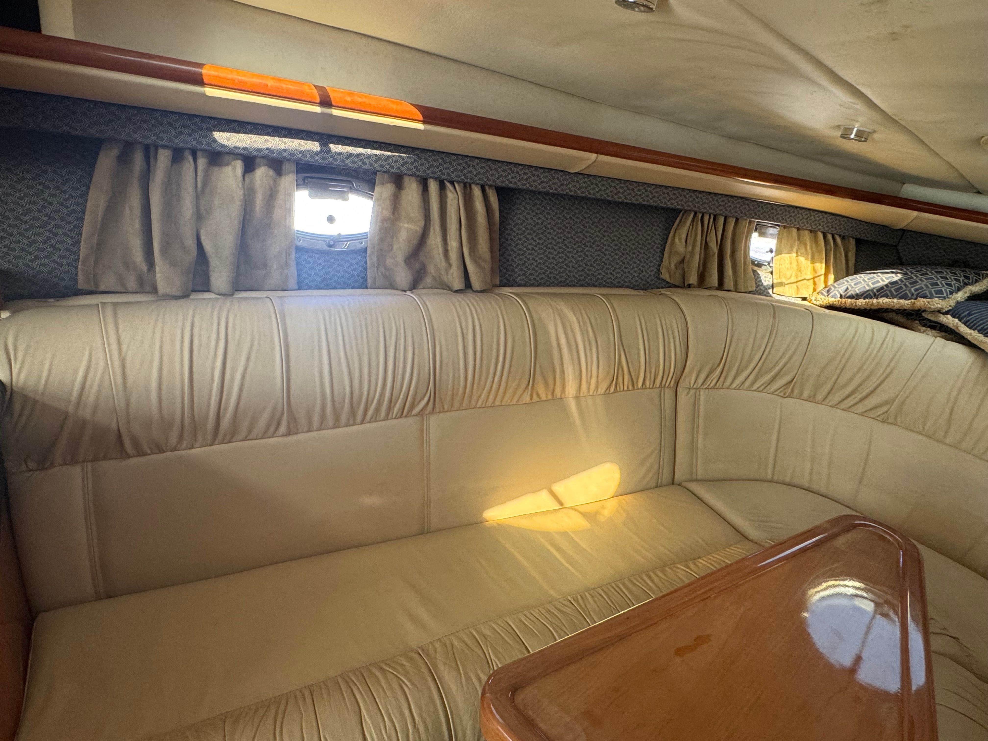 Interior of a 2003 Cobalt 360 with beige upholstered sofa and wooden table.