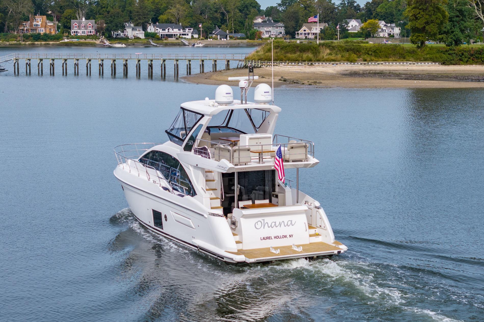 Azimut Fly 50 yacht cruising near shoreline, 2020 model, with American flag displayed.