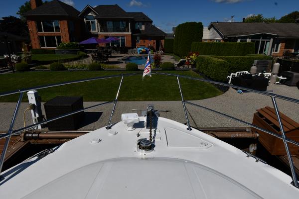 Bow view of 1997 Sea Ray 400 Sundancer docked near a luxurious waterfront home.
