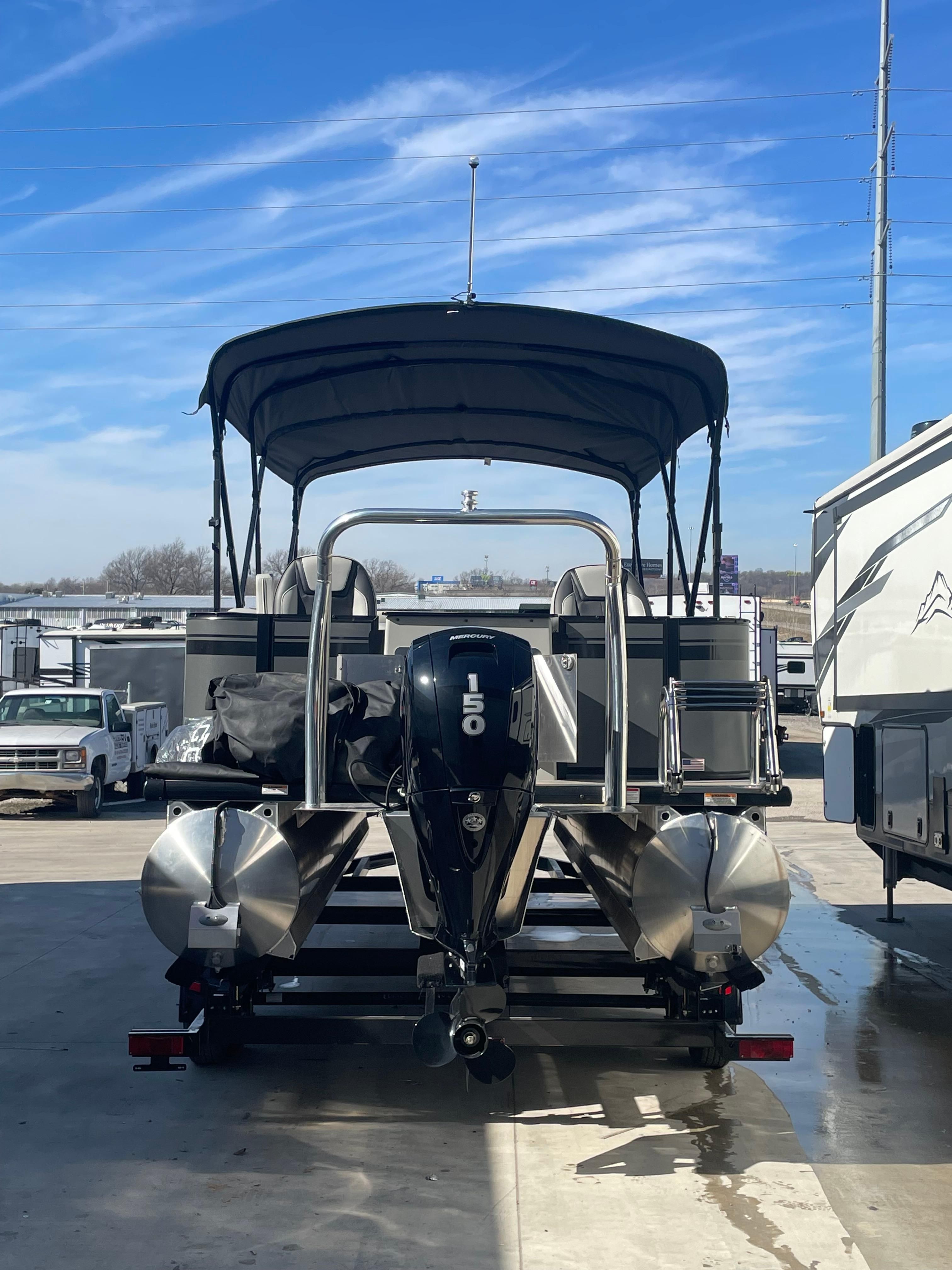 2022 Viaggio Lago pontoon boat with canopy and powerful outboard motor in a parking lot.