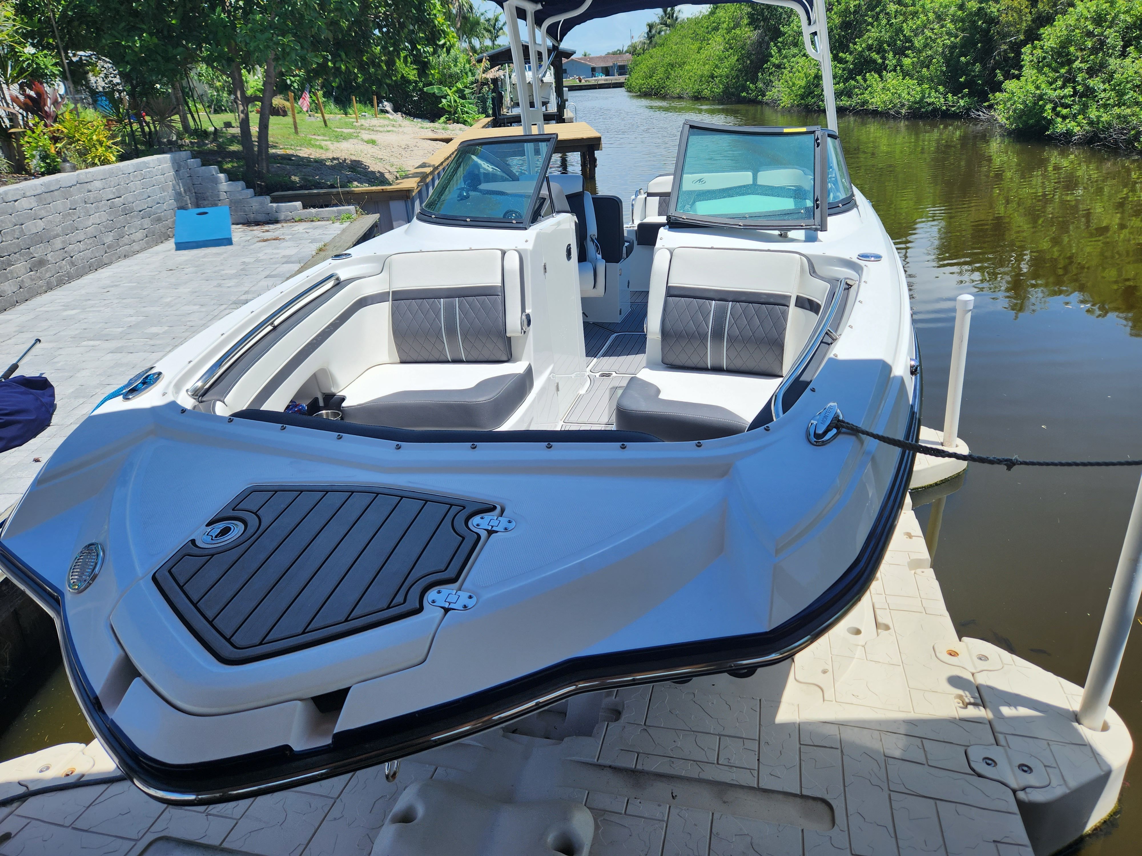 A white 2021 Monterey M6 boat docked at a calm riverside.