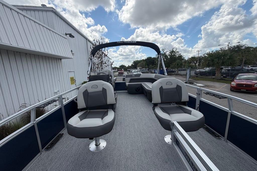 2026 Sun Tracker Bass Buggy 16 XL Select pontoon boat with seating, docked outdoors.