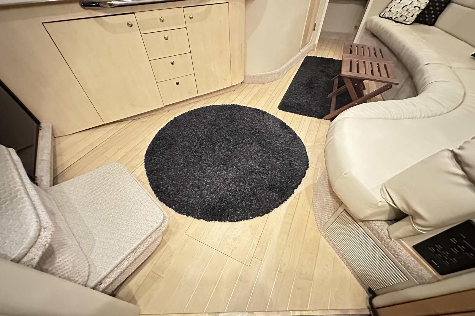 Interior of 2000 Sea Ray 410 Sundancer with beige seating, wooden flooring, and black rug.