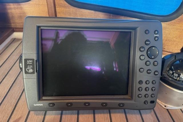 Garmin GPS device on 1983 Nordic Tug 26 boat, displayed on wooden surface.