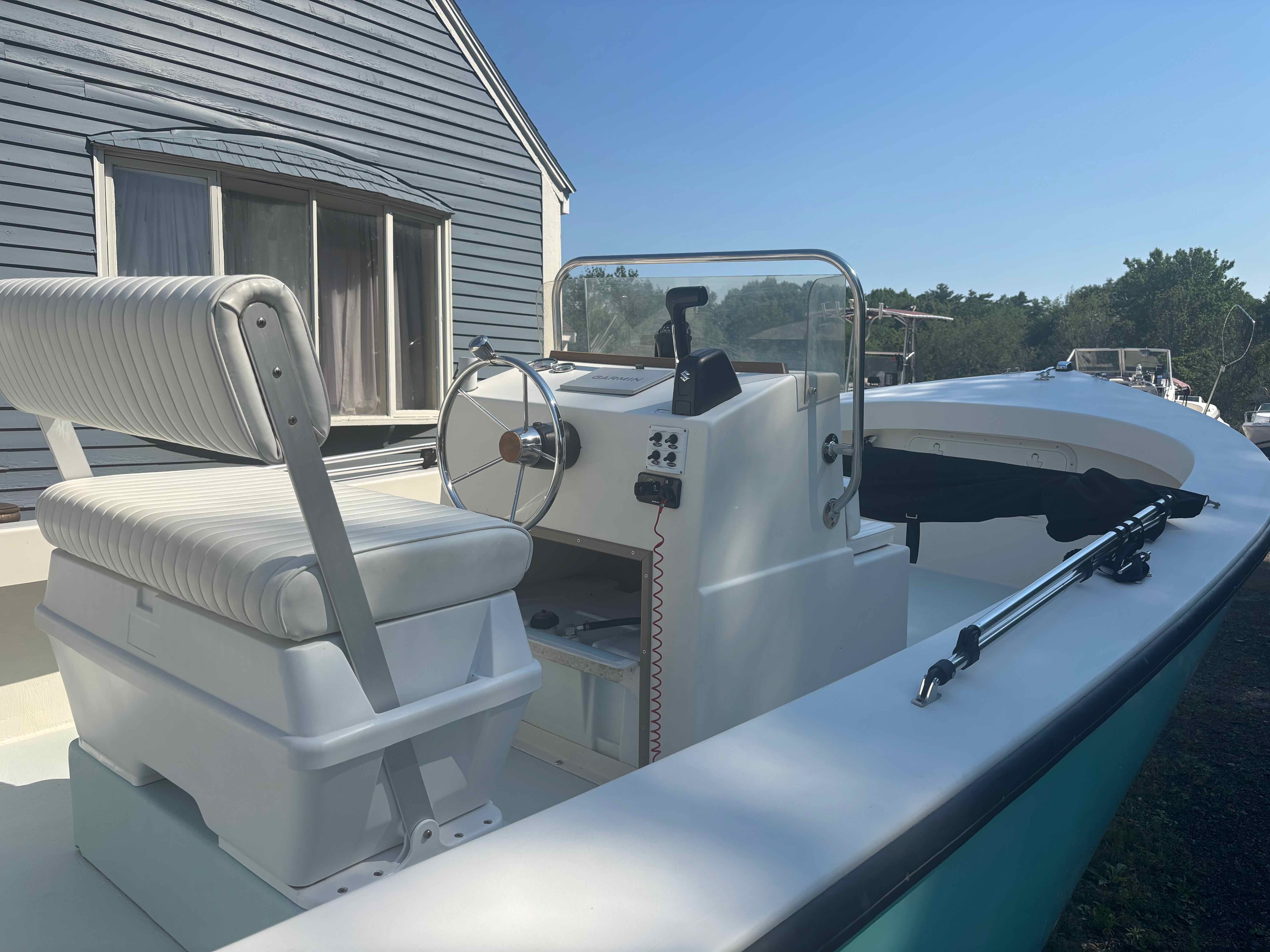 A 2016 Surfside 21 Center Console boat on a trailer next to a house.