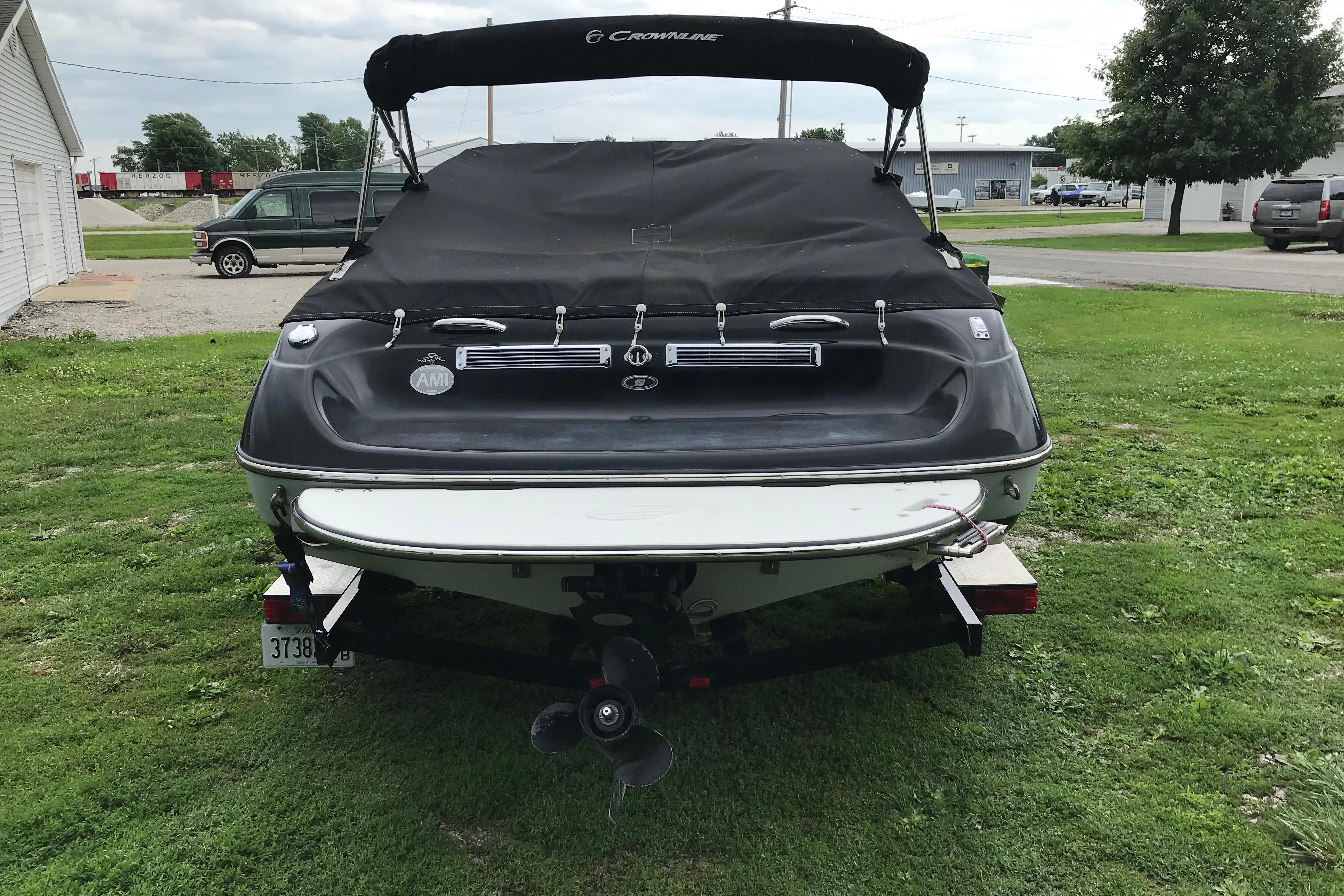 2015 Crownline 18 SS boat with cover, parked on grass, rear view.