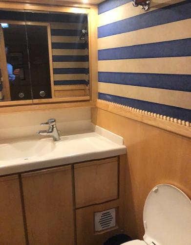 Bathroom interior of a 1997 Bertram Convertible yacht with striped wallpaper.