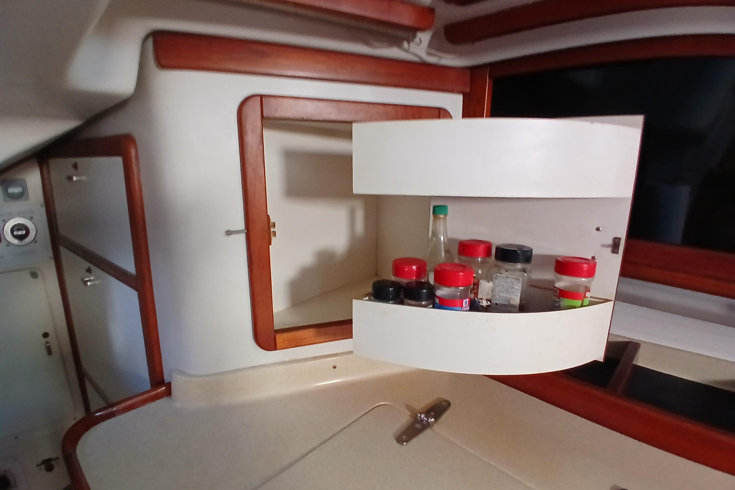 Interior of 1995 Catalina 42 MkII sailboat with spice rack in open cabinet.