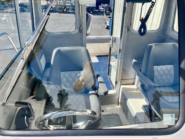 Interior of 2023 Defiance Admiral 220 EX boat with steering wheel and seating.