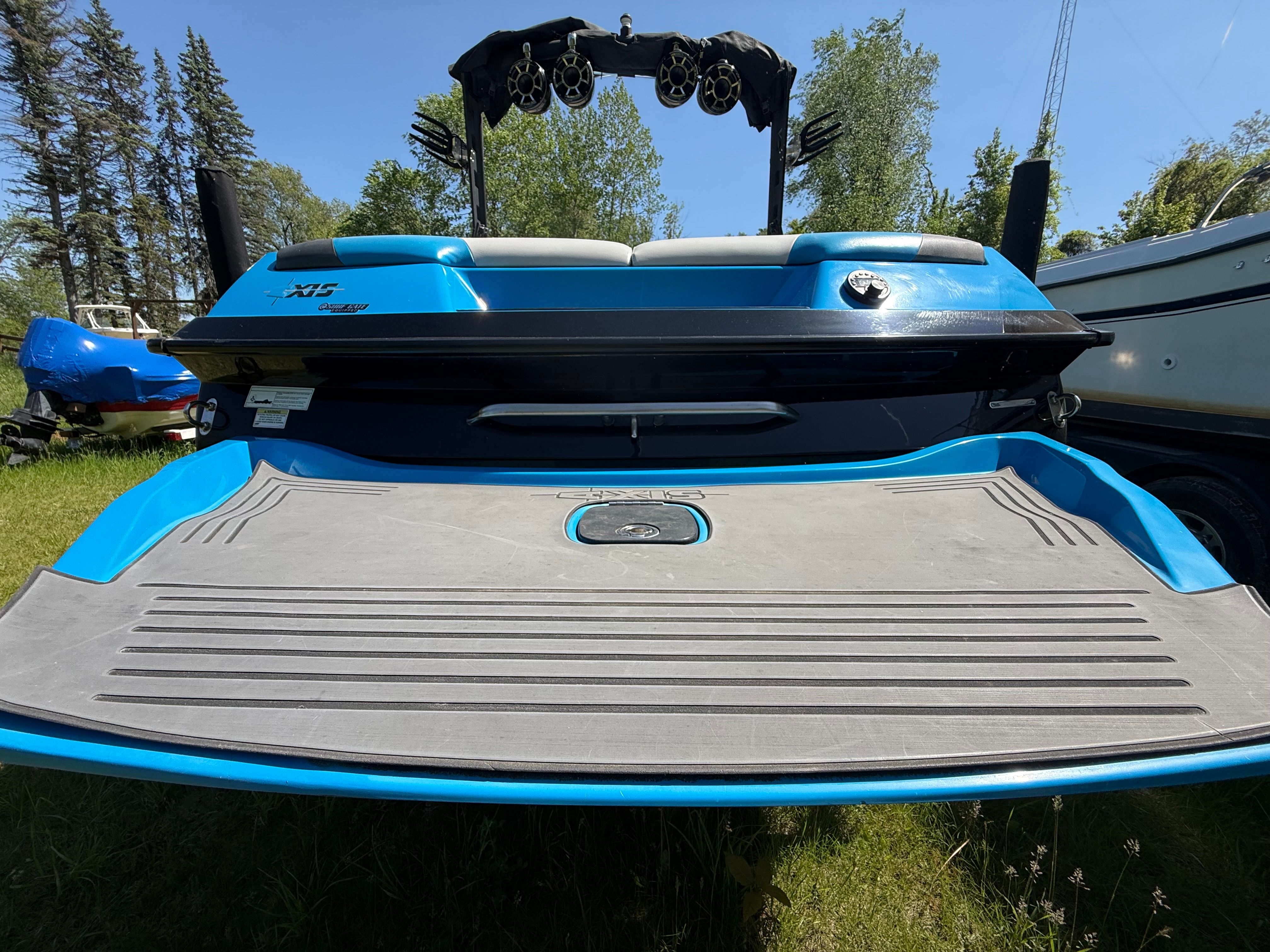 Rear view of a blue 2015 Malibu Axis A20 boat on grass.