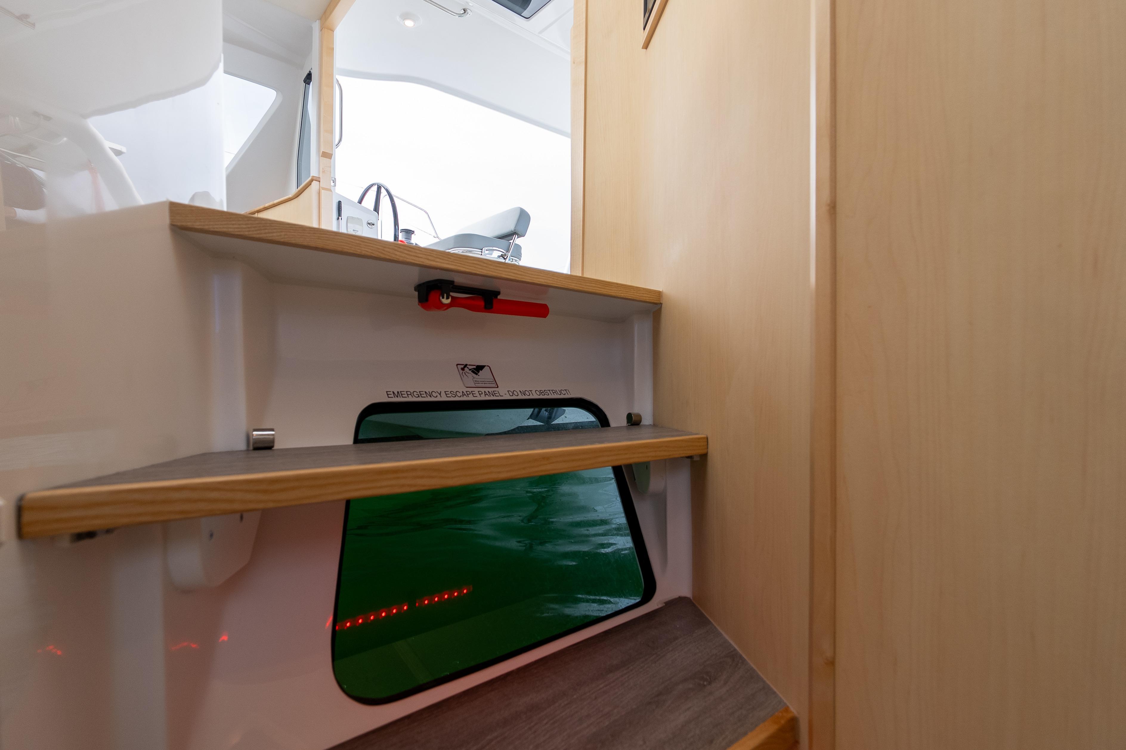 Interior view of 2026 Seawind 1160XL yacht, featuring wooden steps and an emergency escape panel.