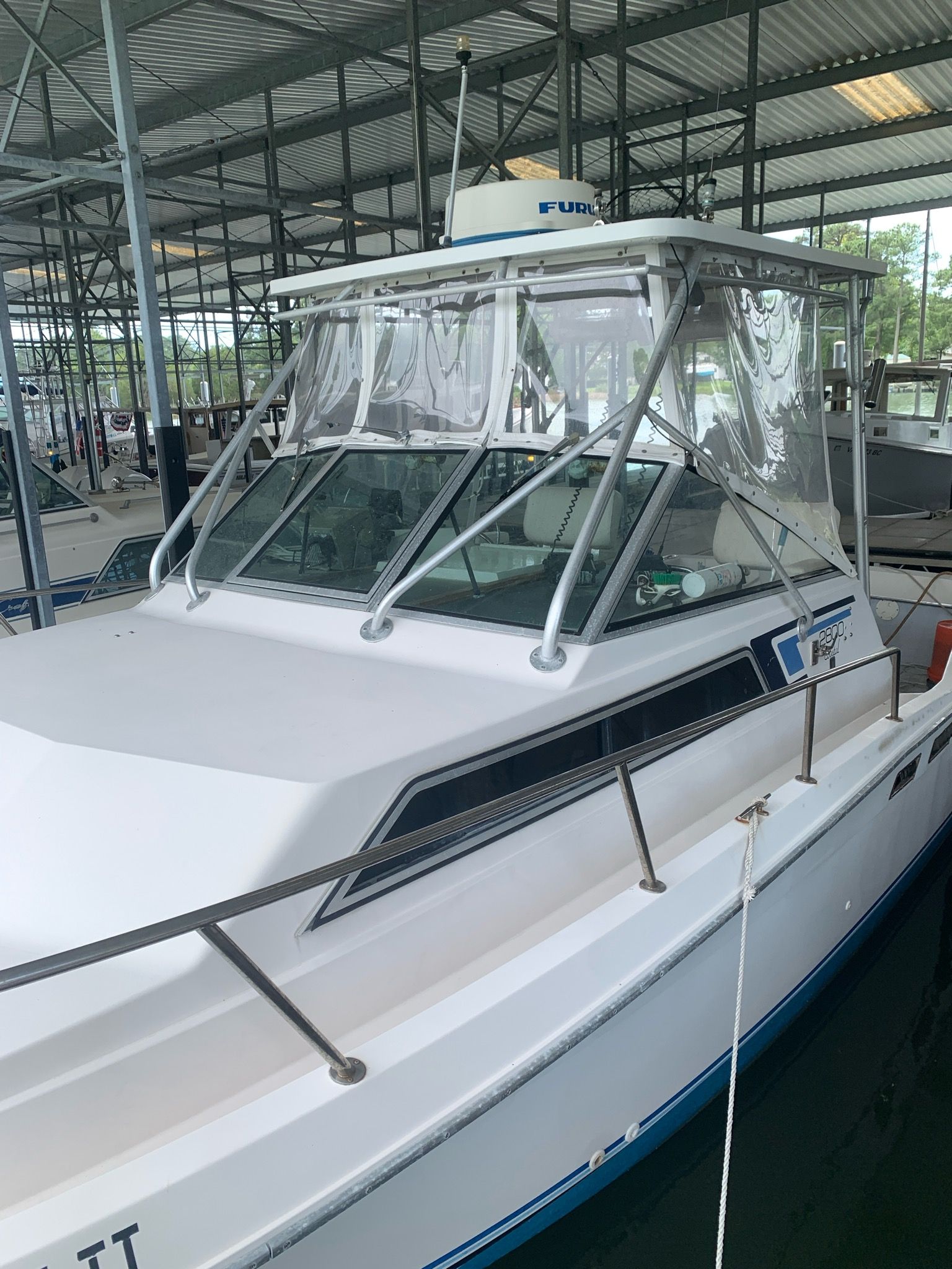 A 1987 Wellcraft COASTAL boat in a covered dock, featuring a white cabin and clear windows.