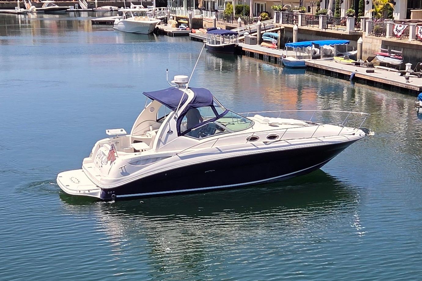 2006 Sea Ray Sundancer 320 yacht docked in a marina, featuring sleek design and blue canopy.